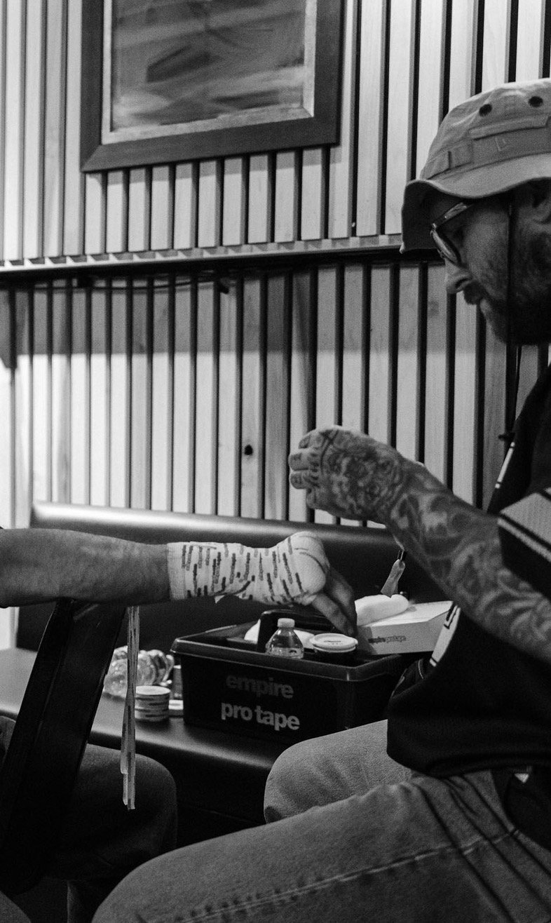 A person receiving a tattoo on their arm at a tattoo studio, with tattoo equipment on the table nearby.