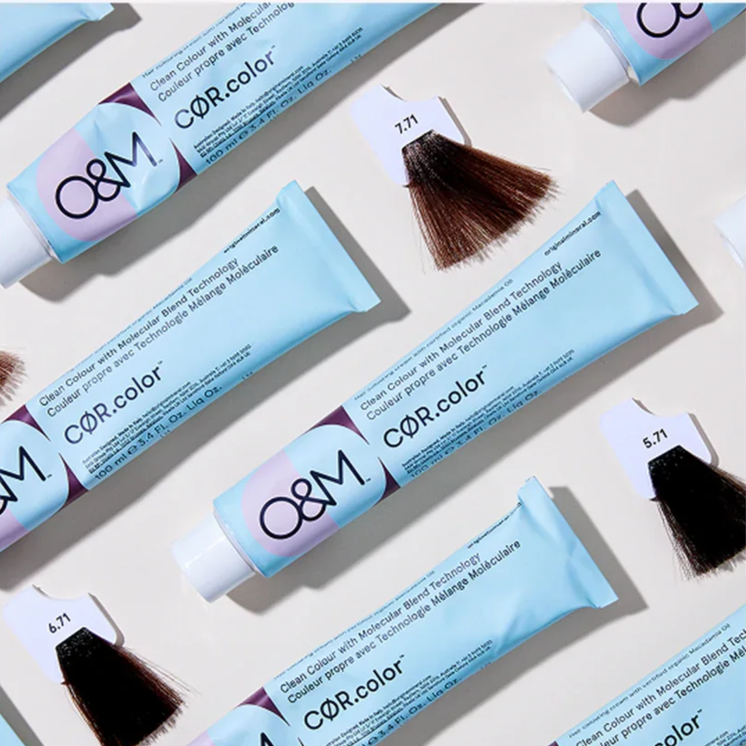 Multiple tubes of O&M brand hair dye in light blue packaging, with hair color swatches labeled 6.71, 7.71, and 5.71, and hair samples showing different shades of brown and black.