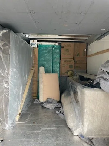 Storage unit with boxes, wrapped furniture, and packed items.