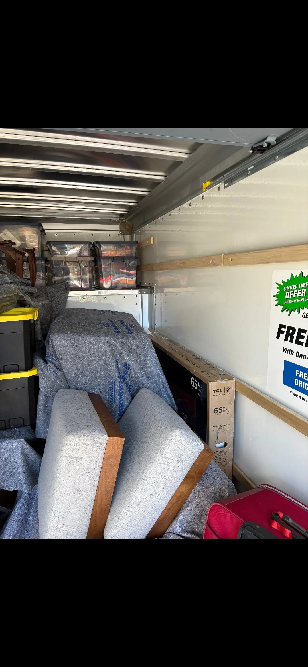 The inside of a moving truck packed with boxes, furniture, and storage bins.