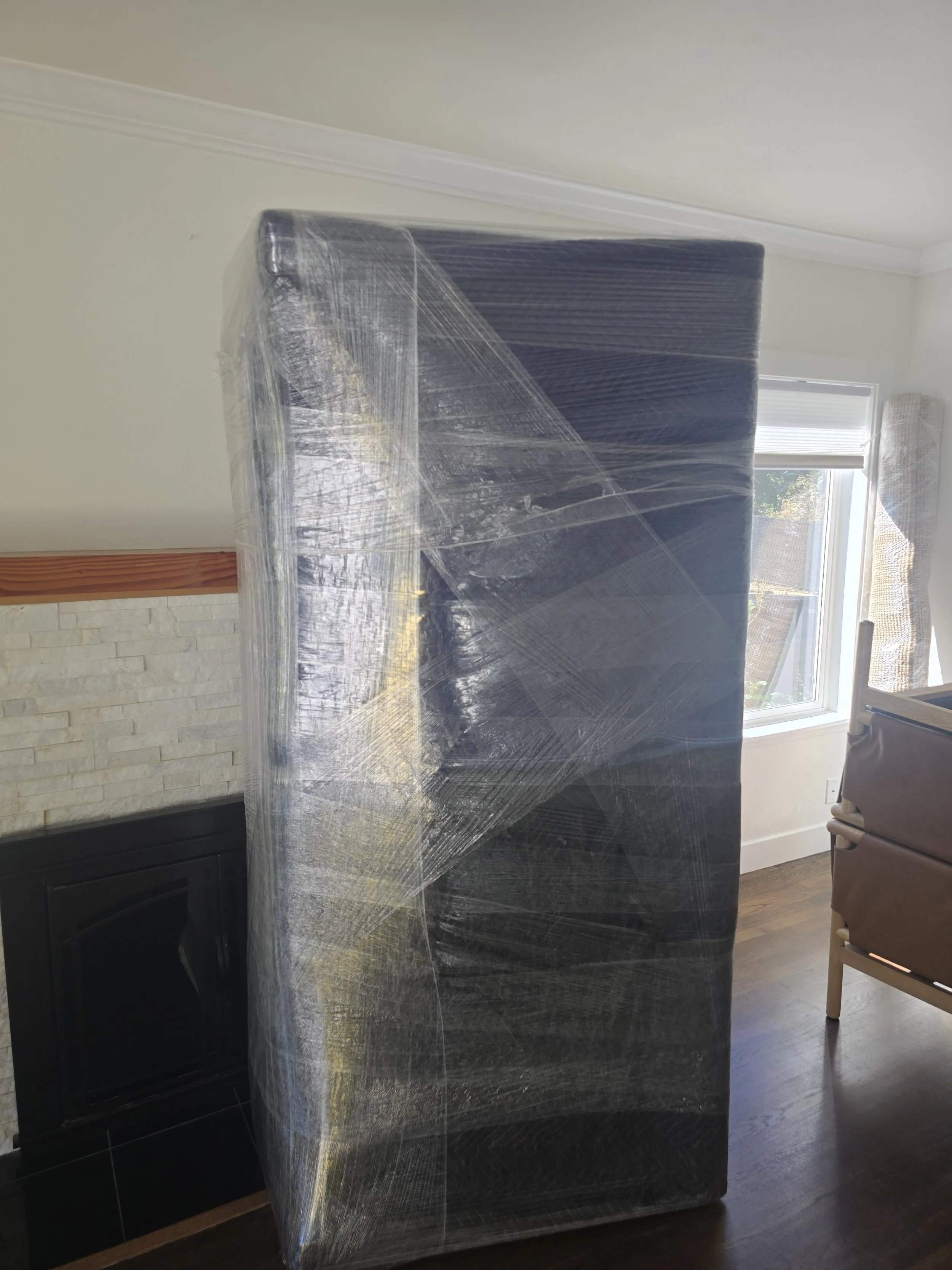 Unwrapped mattress leaning against a wall in a living room.