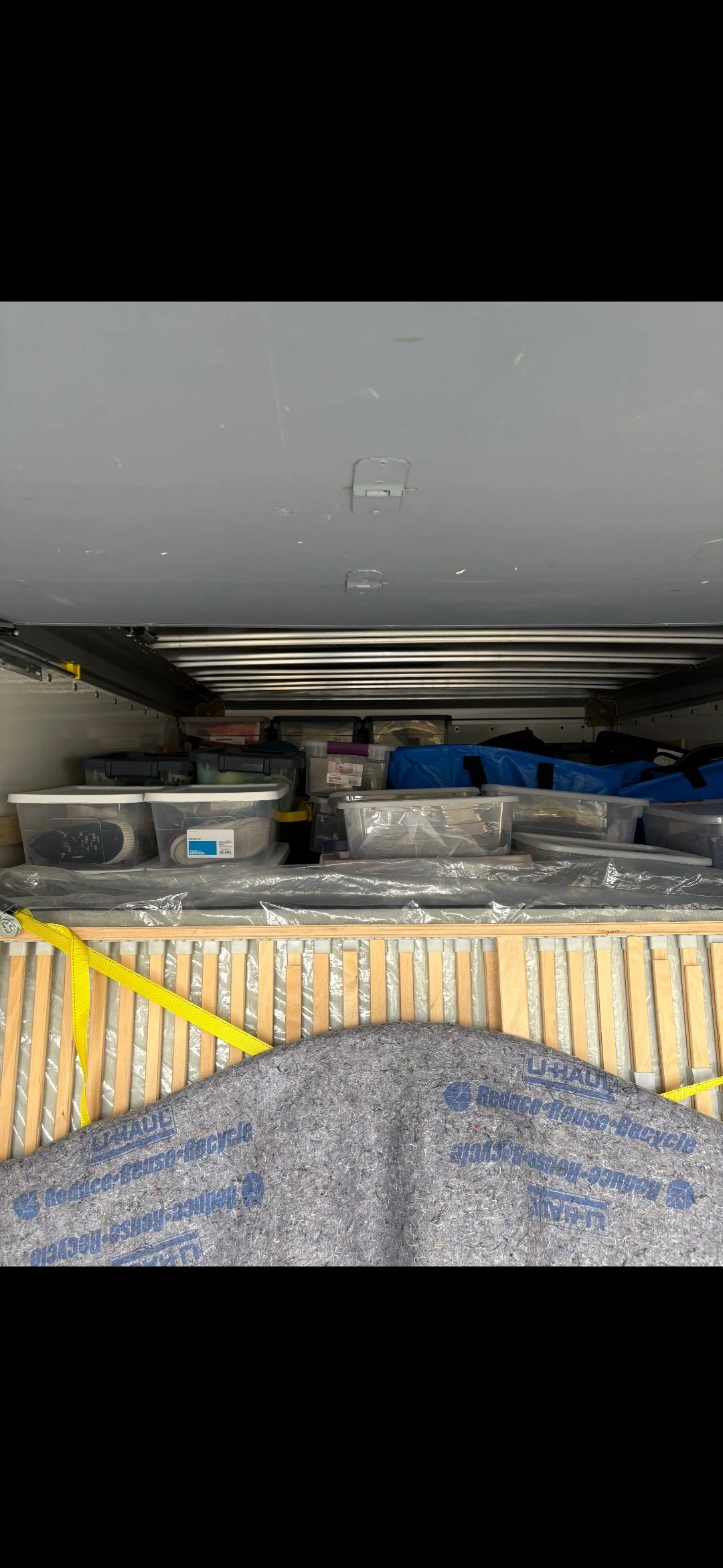 Interior of a truck with storage bins, boxes, and a gray mat.