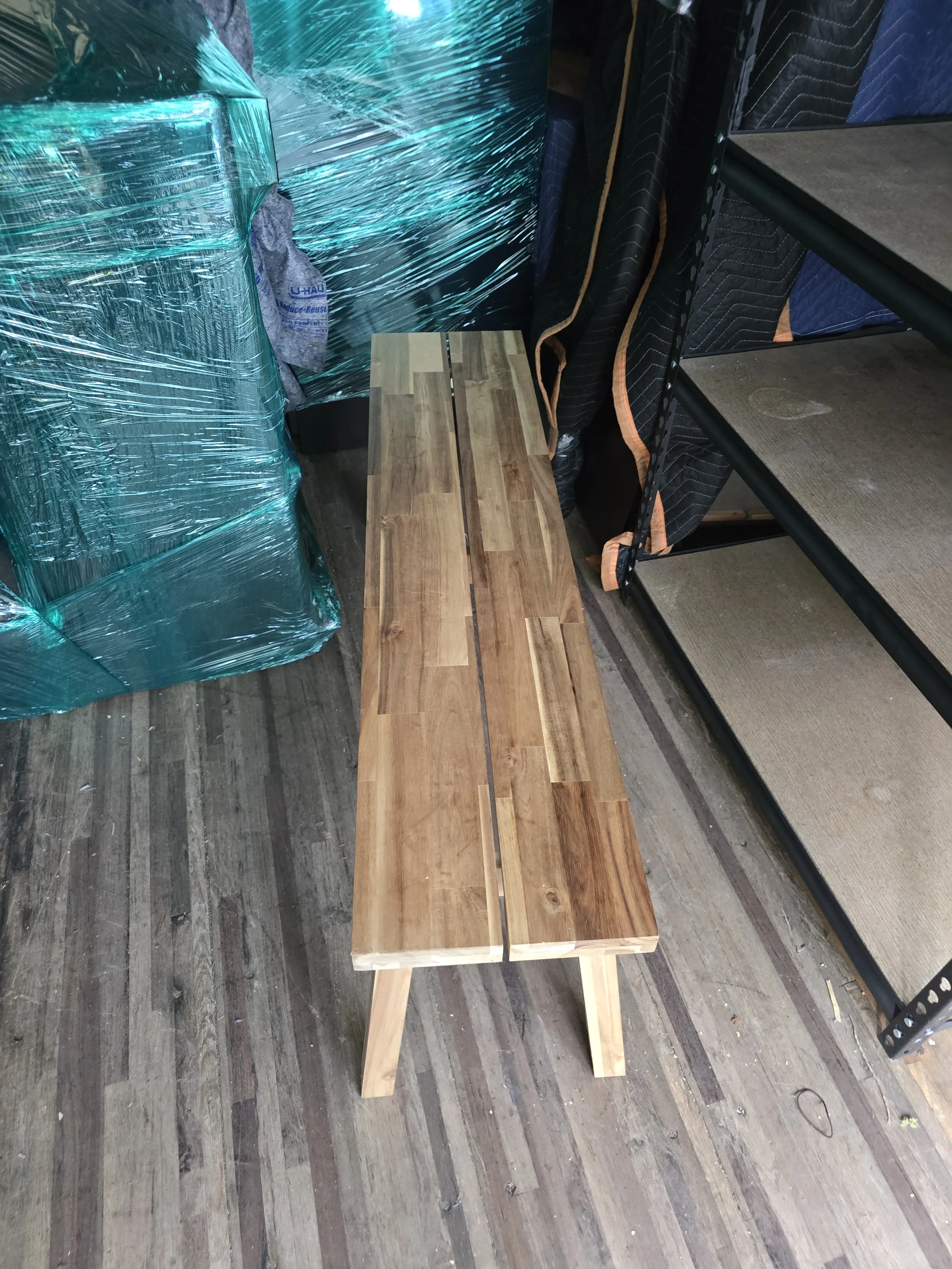 A wooden bench with a slatted top placed on a wooden floor.