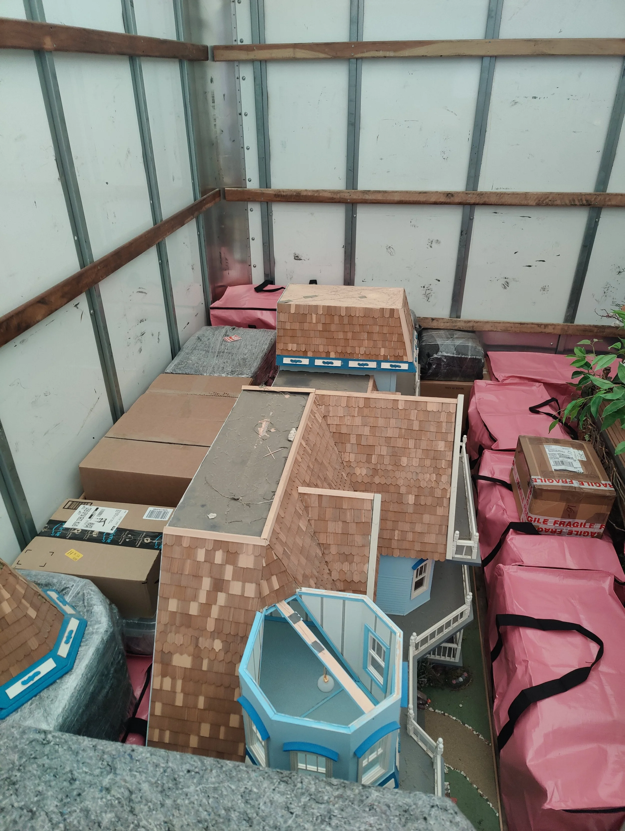 A collection of miniature dollhouses and unpacked boxes inside a storage unit or garage.