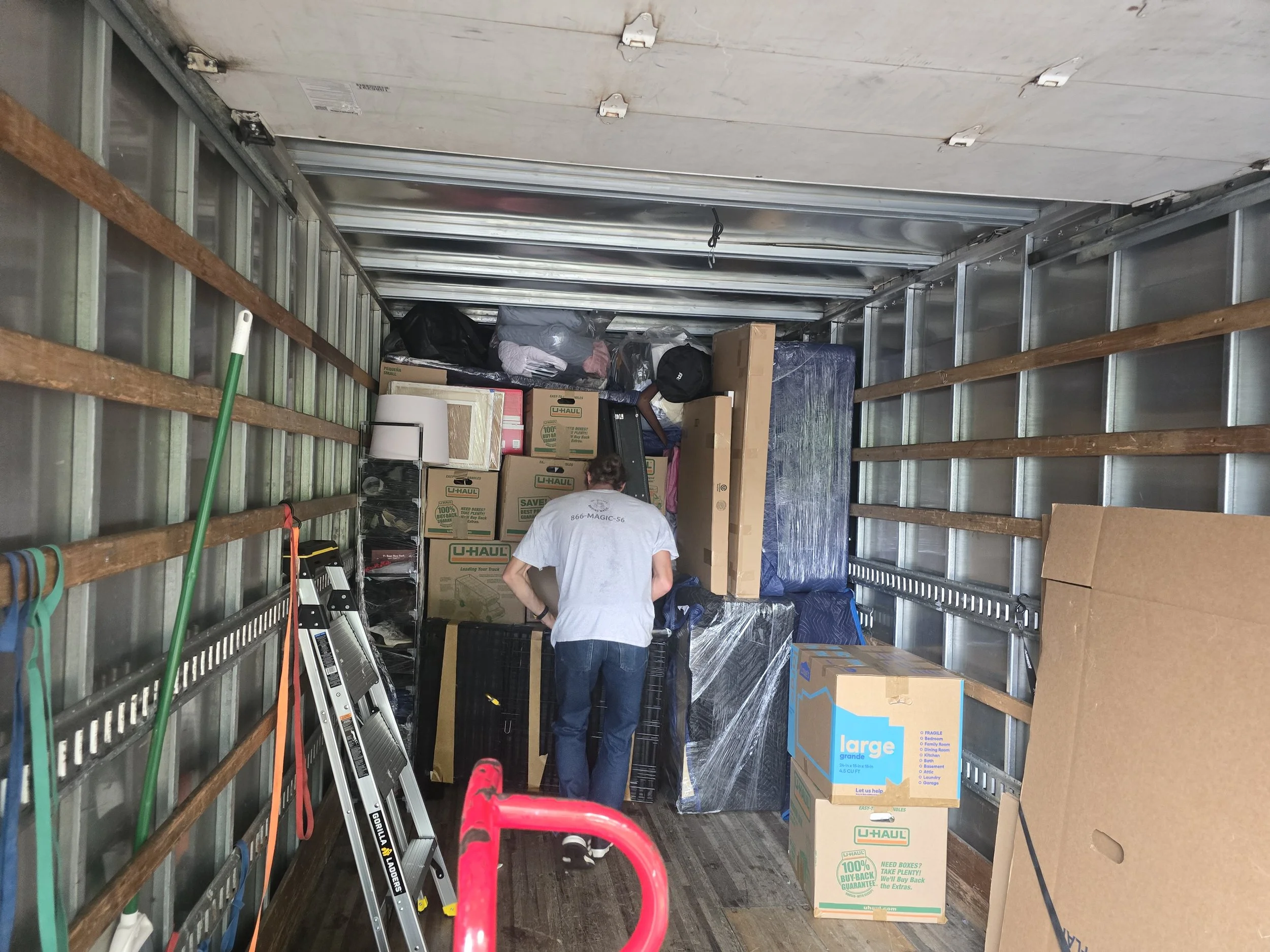 Inside a moving truck filled with packed boxes, household items, and a person organizing.