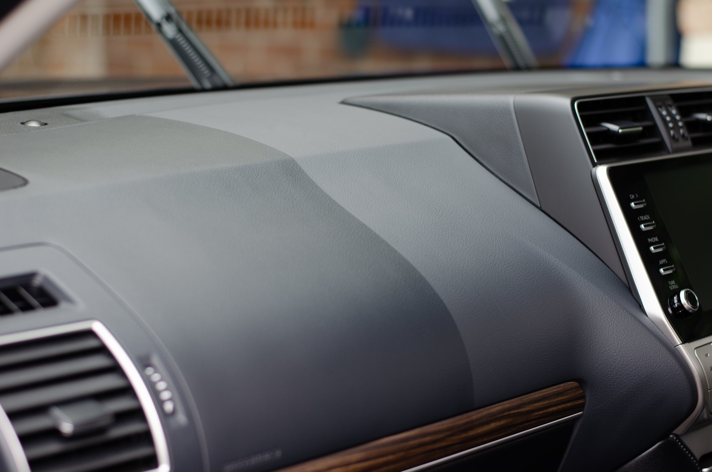 Close-up of a car's gray dashboard and part of the center console with an air vent and a digital display screen.