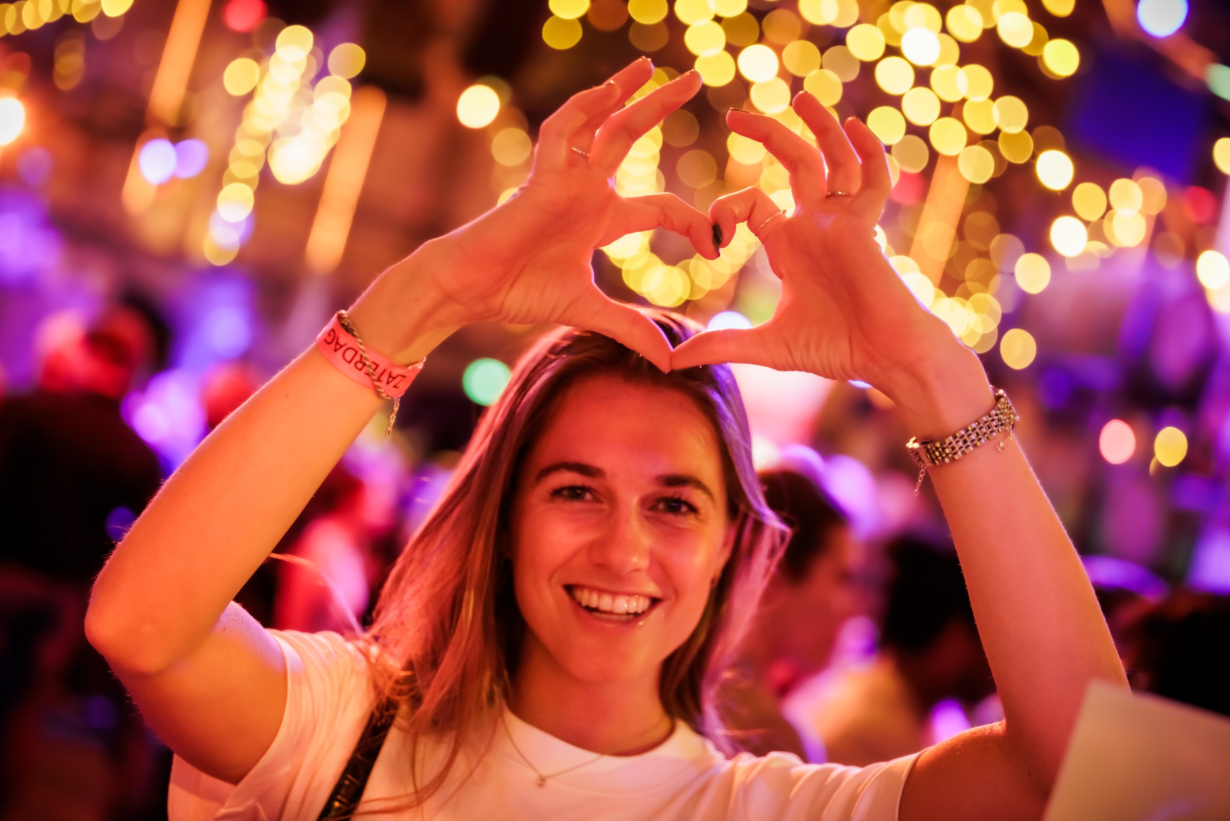 Vrouw die in een feestelijke omgeving foto maakt en een hart vormt met haar handen.