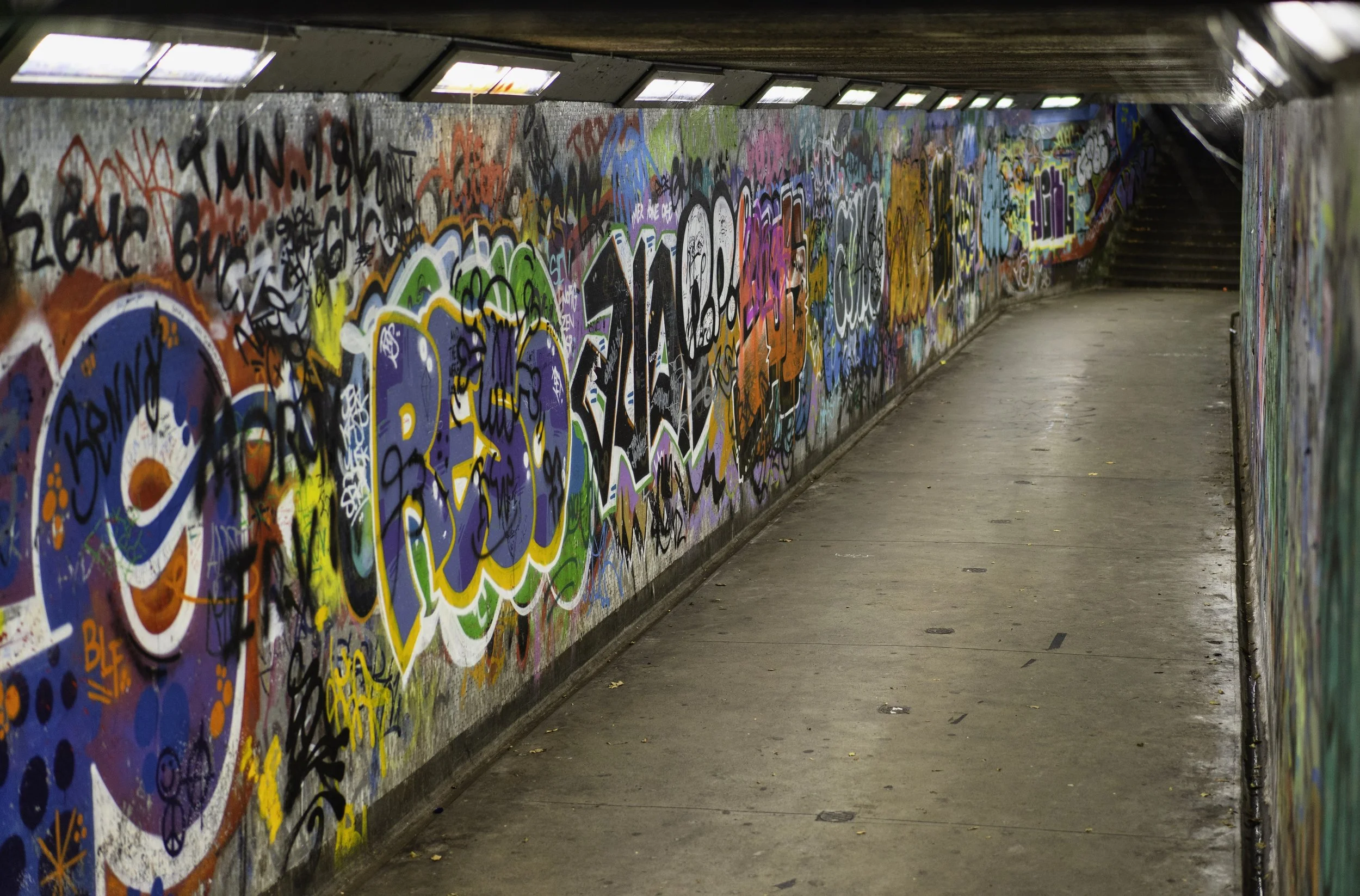 Graffiti-covered urban tunnel with dim lighting.