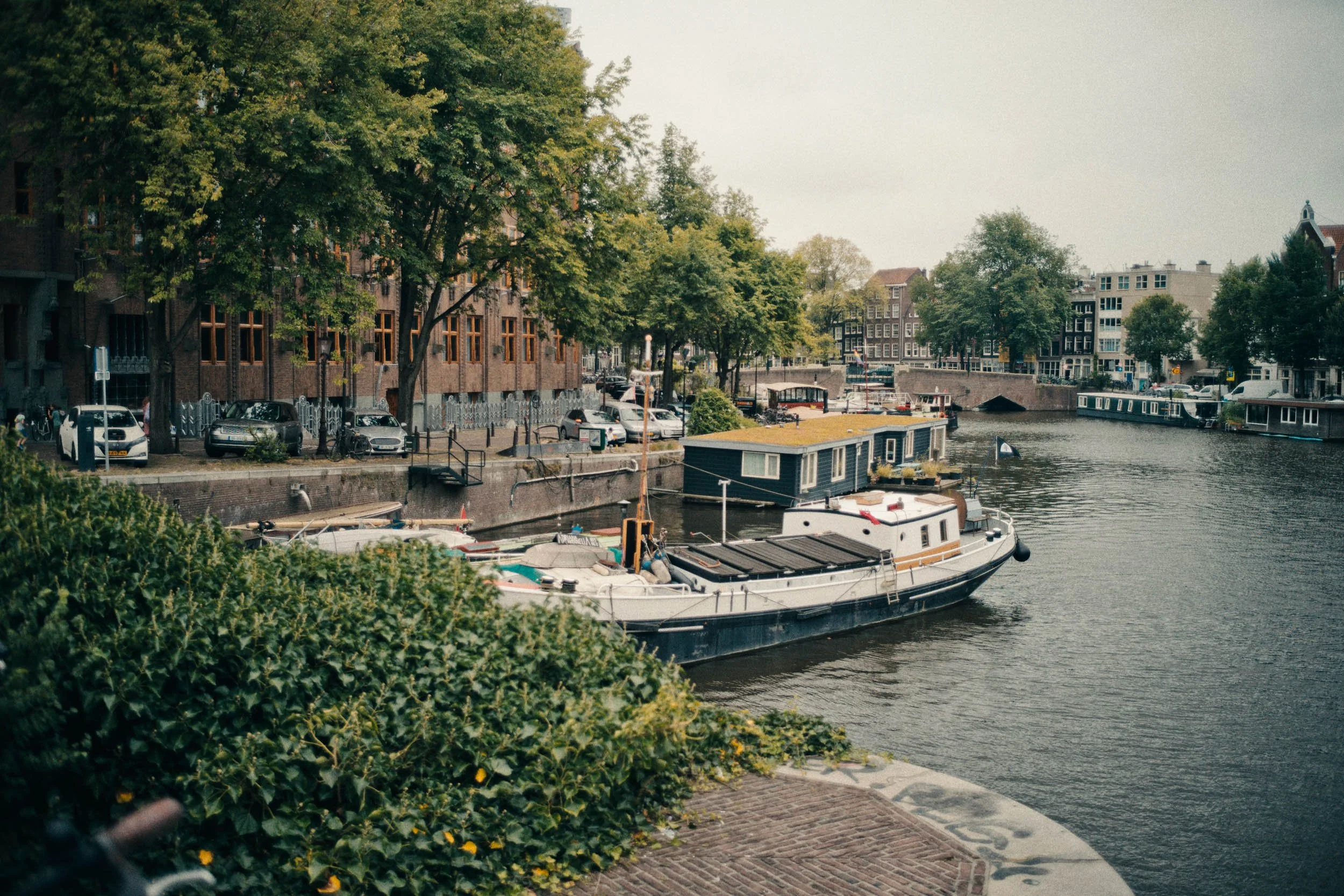Gezicht op een kanaal met boten en omringende gebouwen in een stad, met bomen langs de kade.