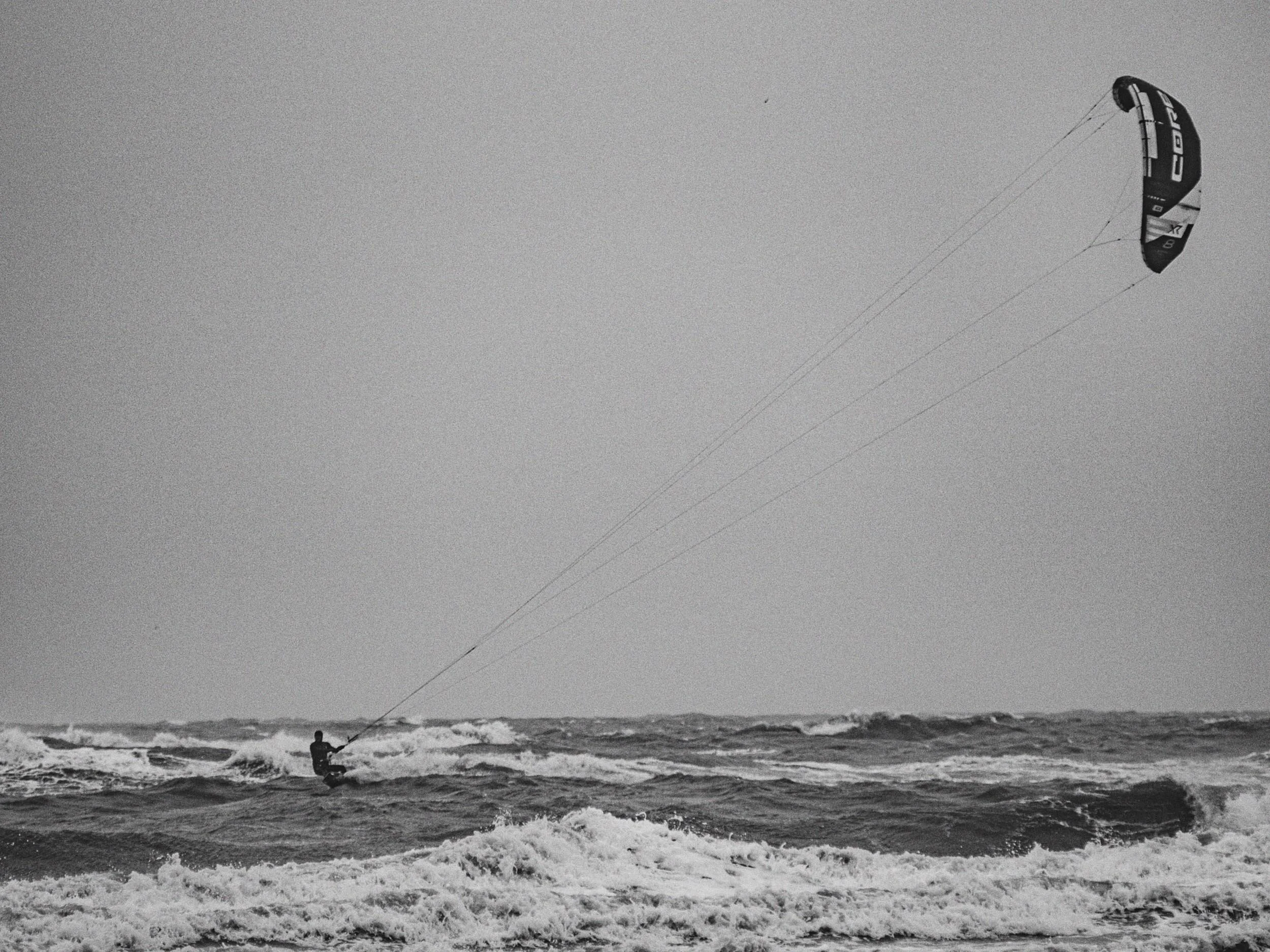 Een persoon die kitesurfen in de golven van de zee.