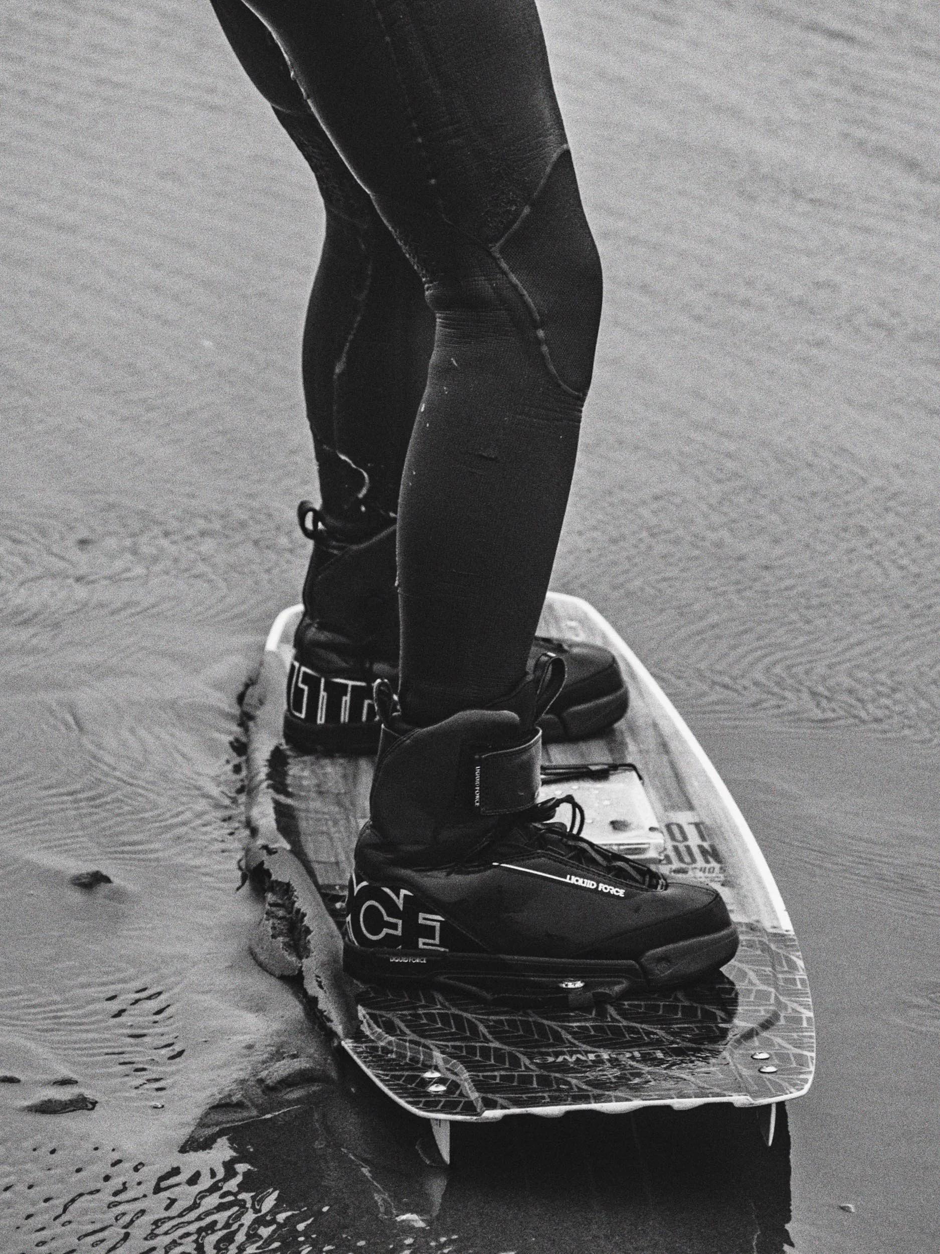 Een persoon op een surfplank met wetsuit op het water.