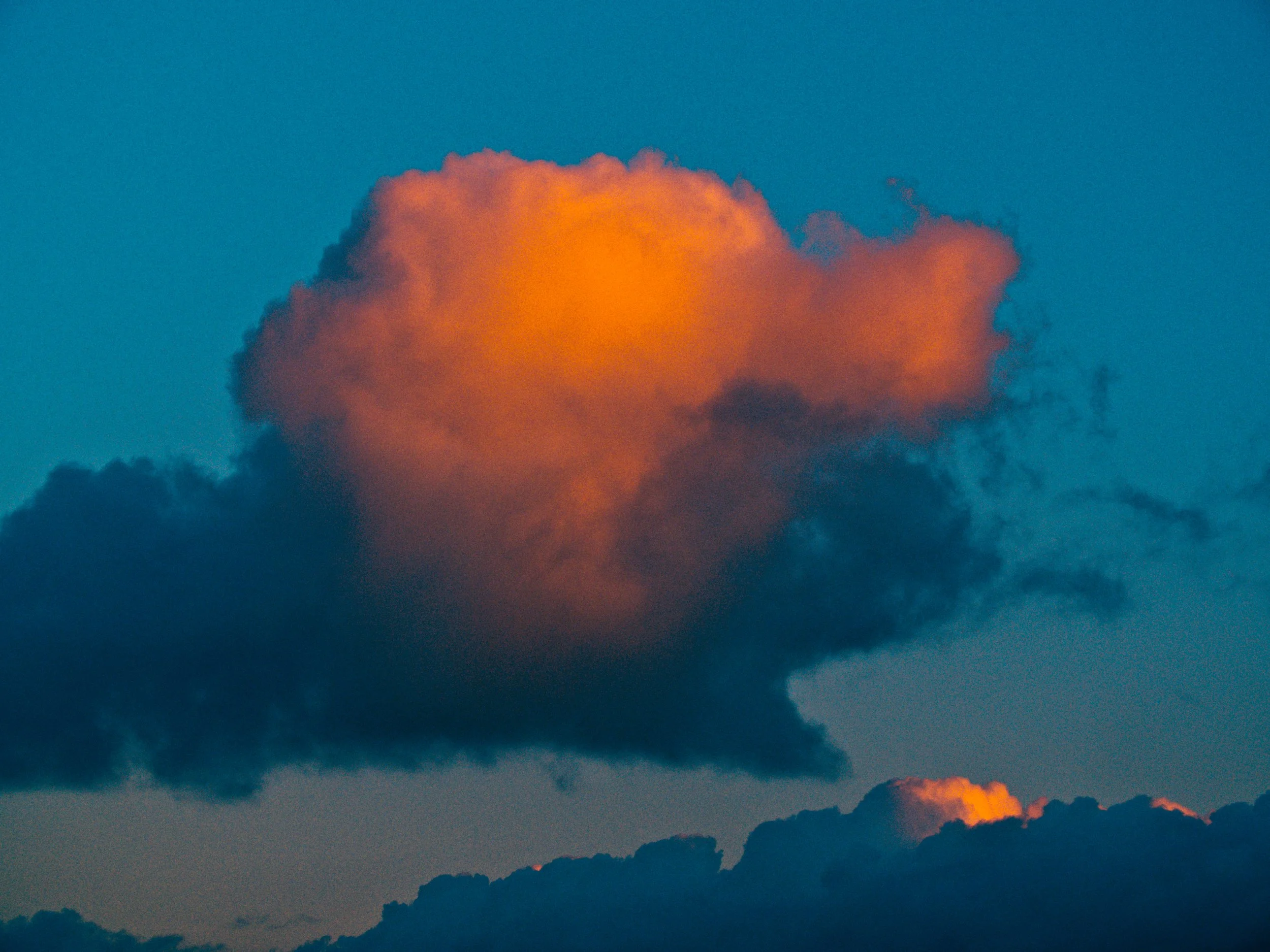 De lucht met een heldere, oranje gekleurde wolk tijdens de ondergang of zonsopgang.