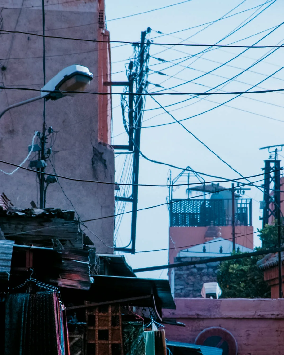 Een straat met elektriciteitskabels en groene planten op de achtergrond, in een stedelijk gebied.