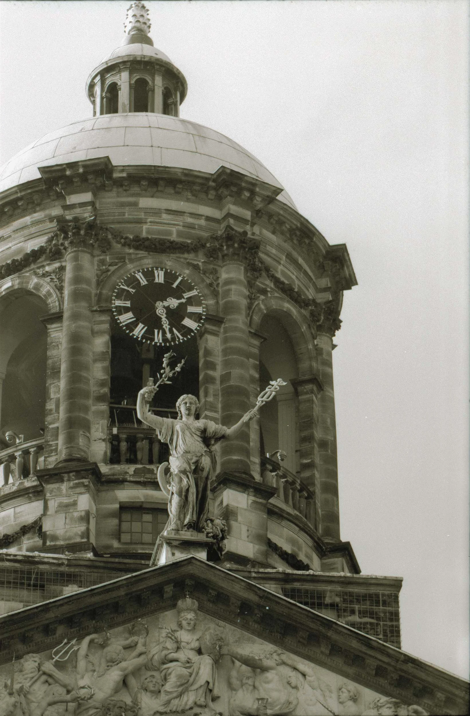 Zicht op een historische stadskerk met een klok en een standbeeld in de gevel, in zwart-wit foto.