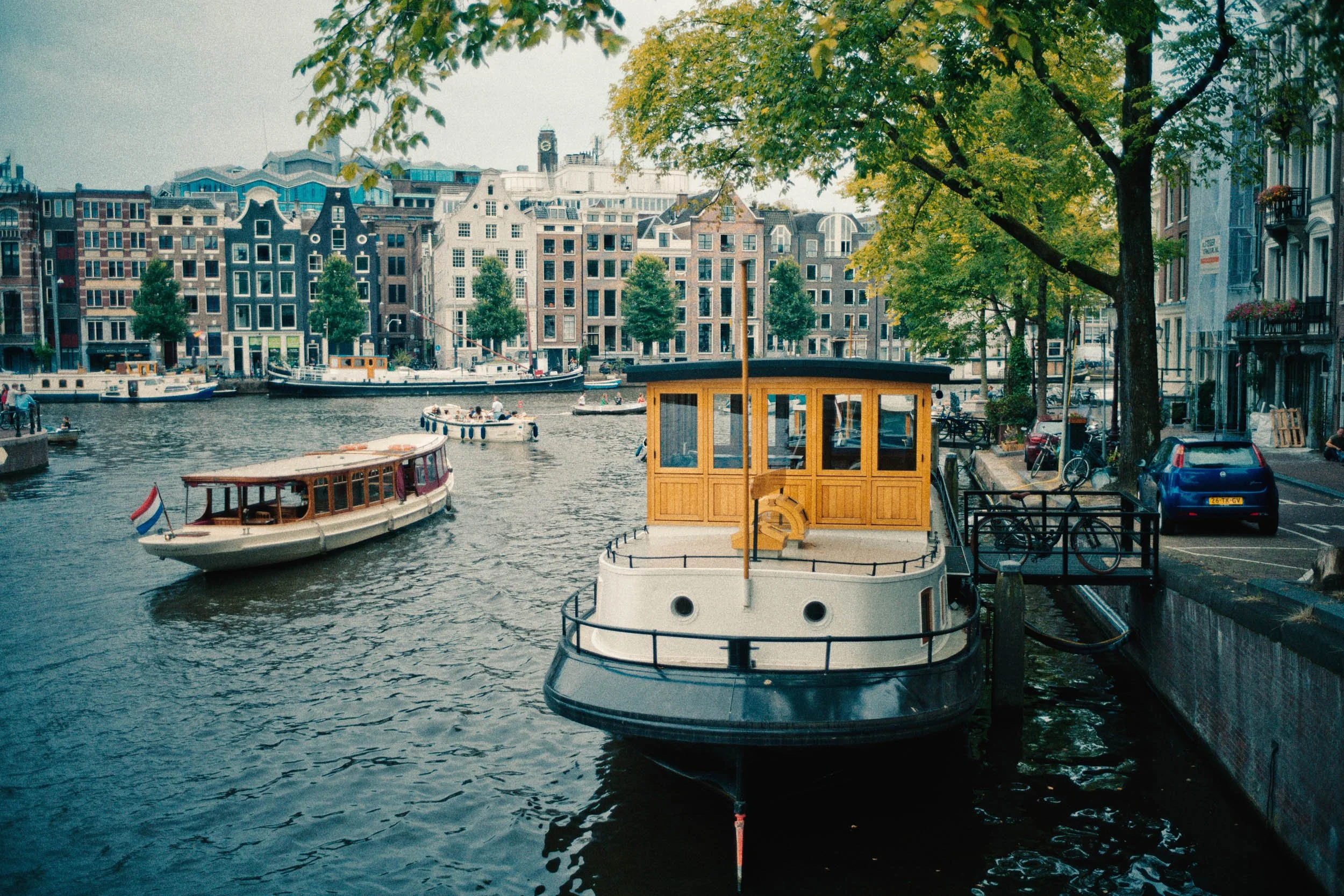 Een kanaal met verschillende boten in een stad met grachtenpanden en bomen.