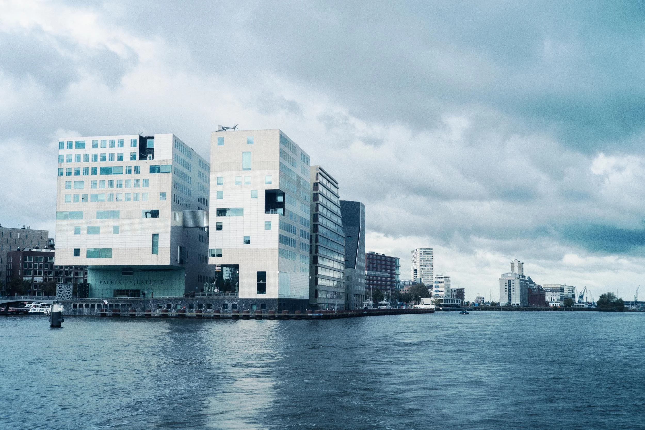 Modern stad met hoge gebouwen langs een rivier onder een bewolkte hemel.
