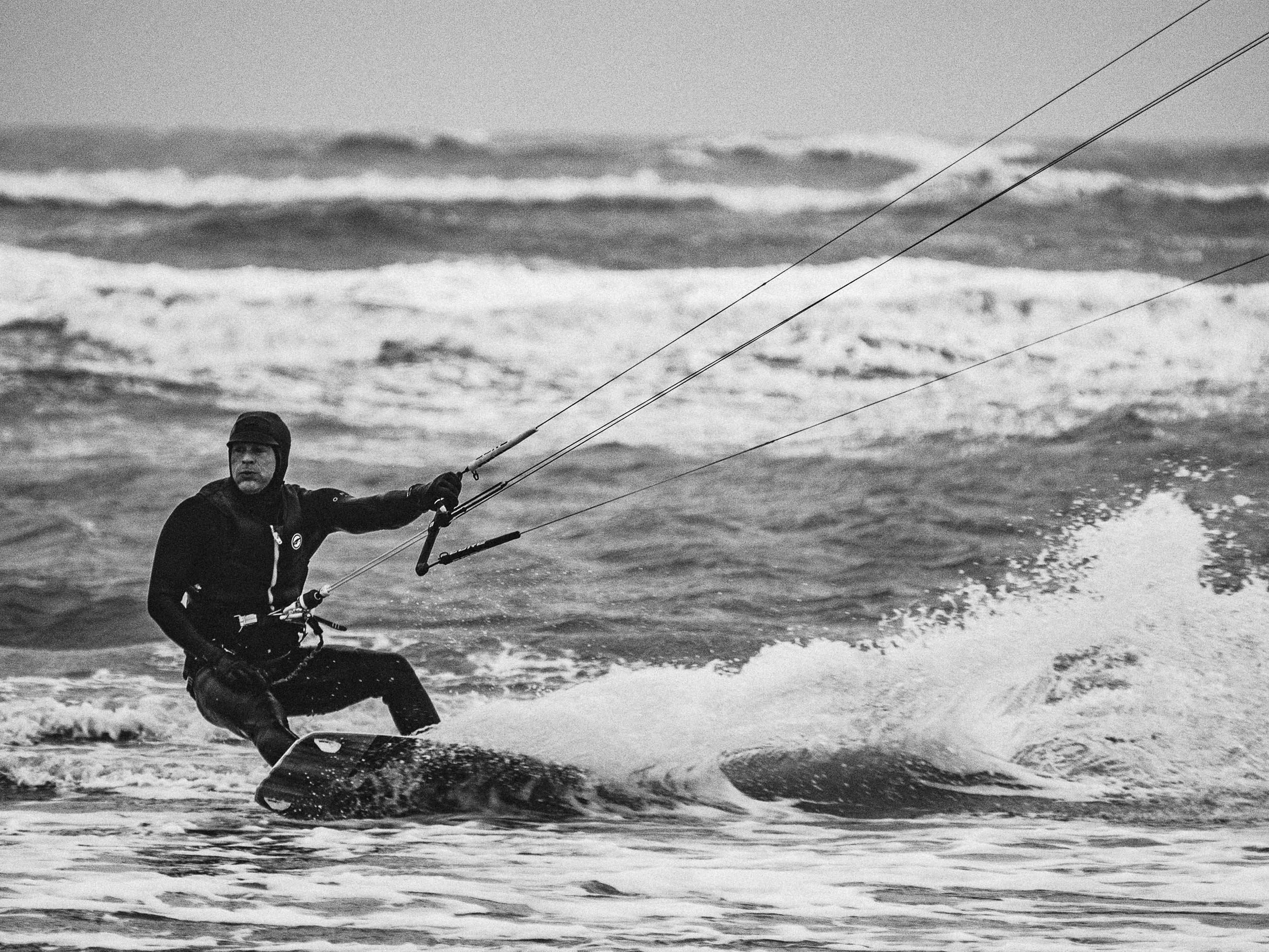 Persoon kitesurfen op de oceaan in zwart-wit.