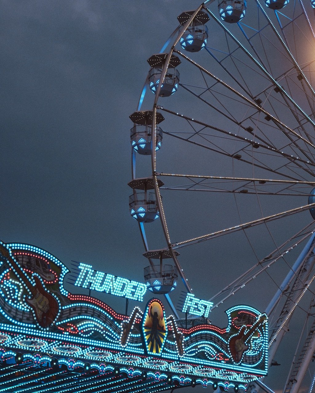 Nighttime view of the Thunder Fest amusement park ride with bright lights and a Ferris wheel in the background.