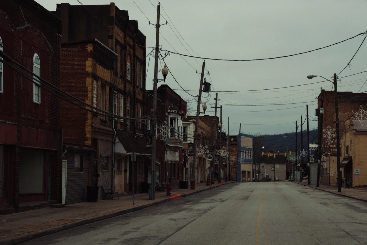 Empty street in a small town or city with old brick buildings, street lamps, and power lines, decorated with snowflake ornaments for winter.