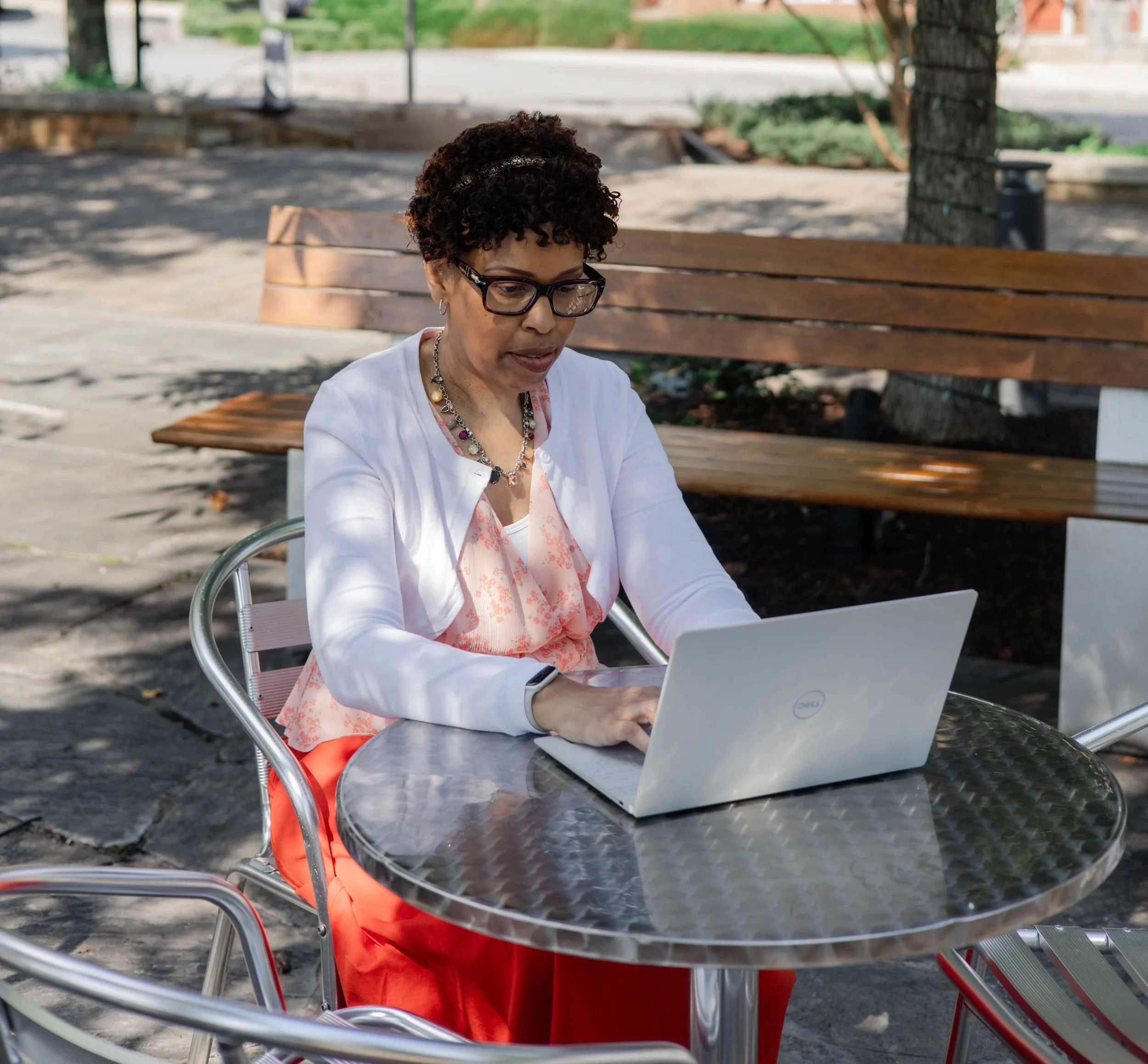 Woman wearing glasses sitting at the table working on the laptop