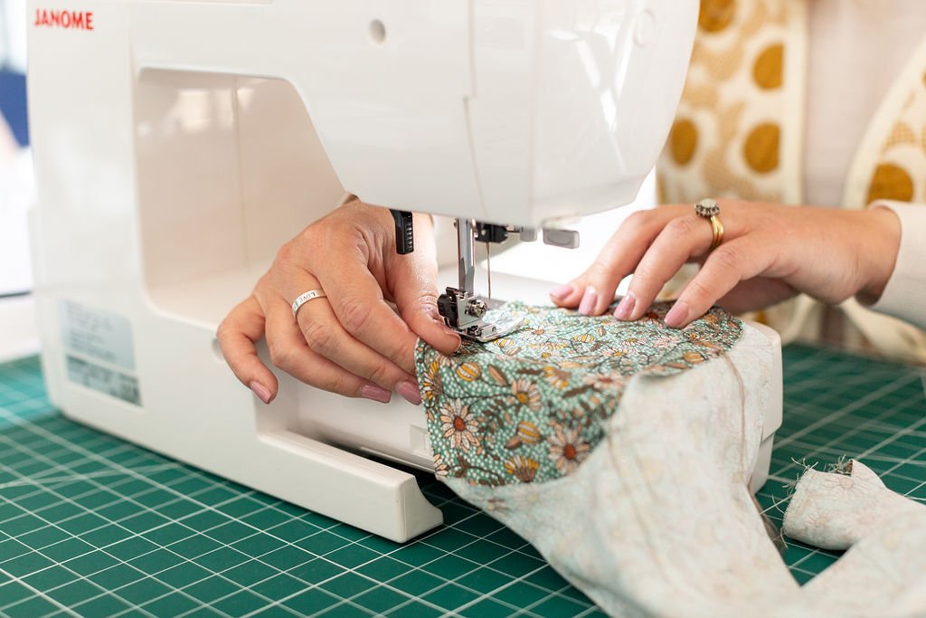 Person using a sewing machine to sew a sleeve into a top.