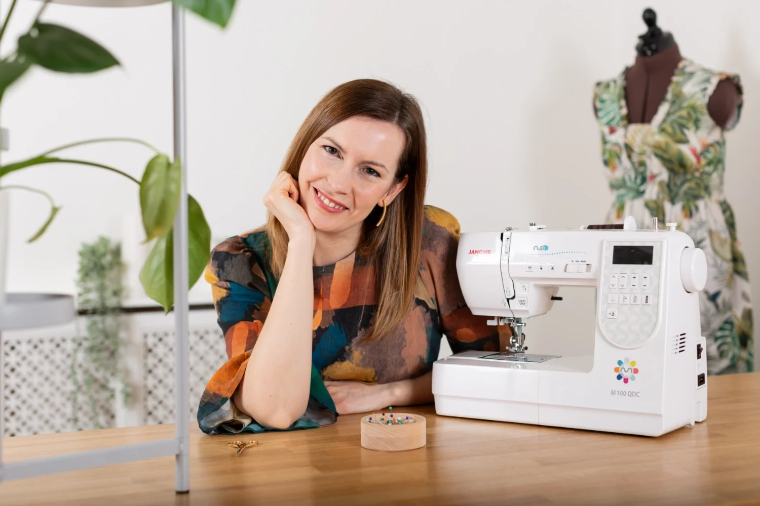 Headshot of Izzy sat at her sewing studio