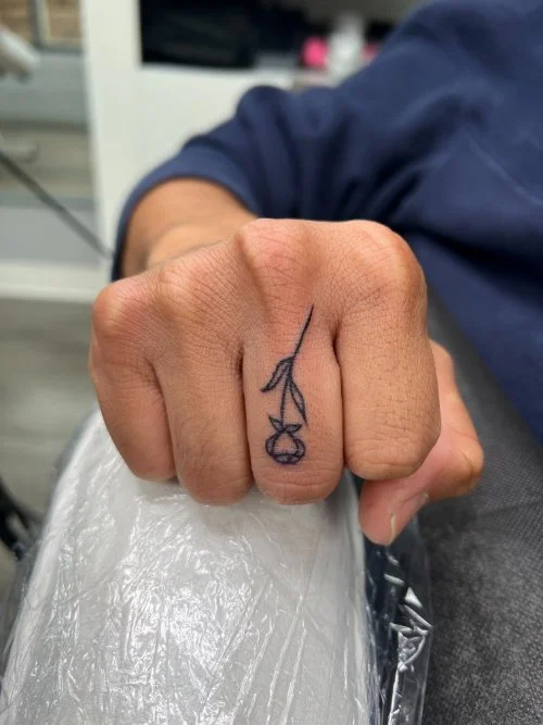 Tiny tattoo on a finger, a Rosé tattoo on a finger.