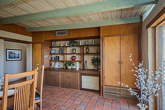 The existing dining with built in shelves, wooden finishes and a warm tile floor