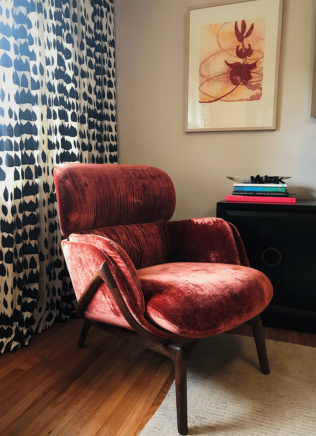 Close up of living-room curtain pattern with black tear drop like shapes on white and a red chair