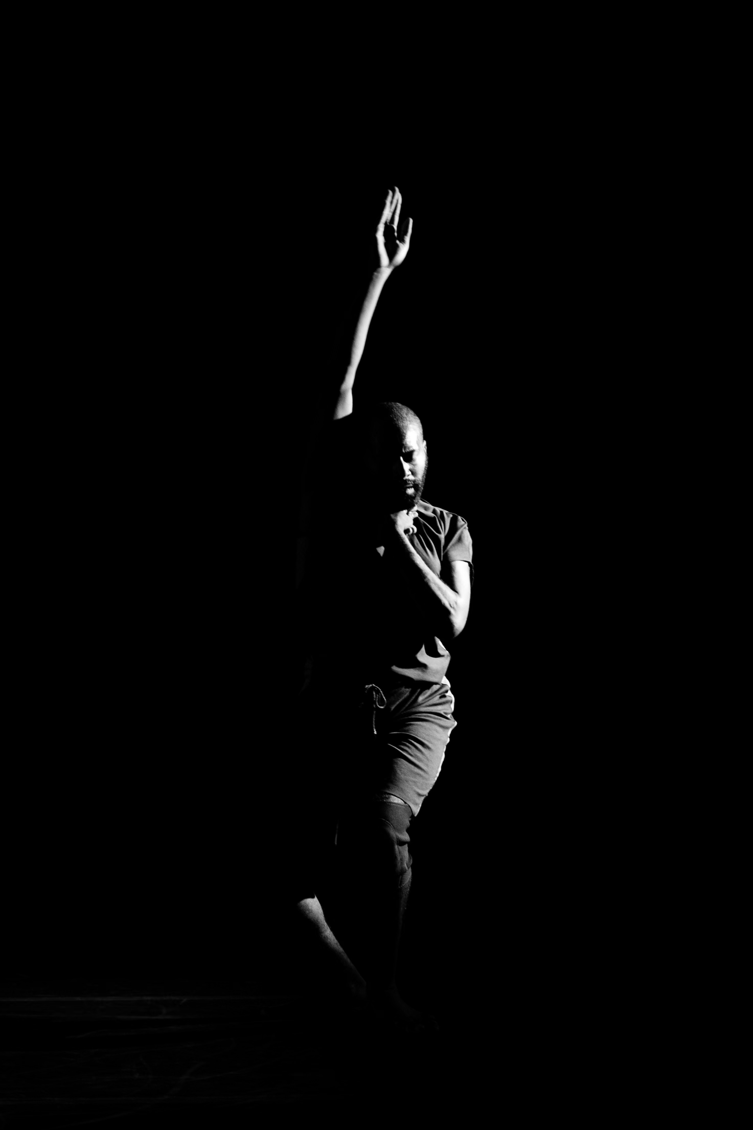 B/W Jerron lifts an arm up in mid dance against a black void