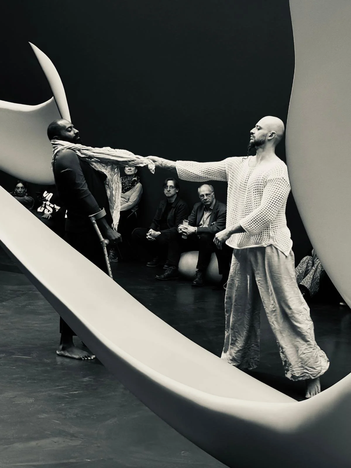 B/W photo of Jerron and Christopher leaning with a fabric at Jerron's neck