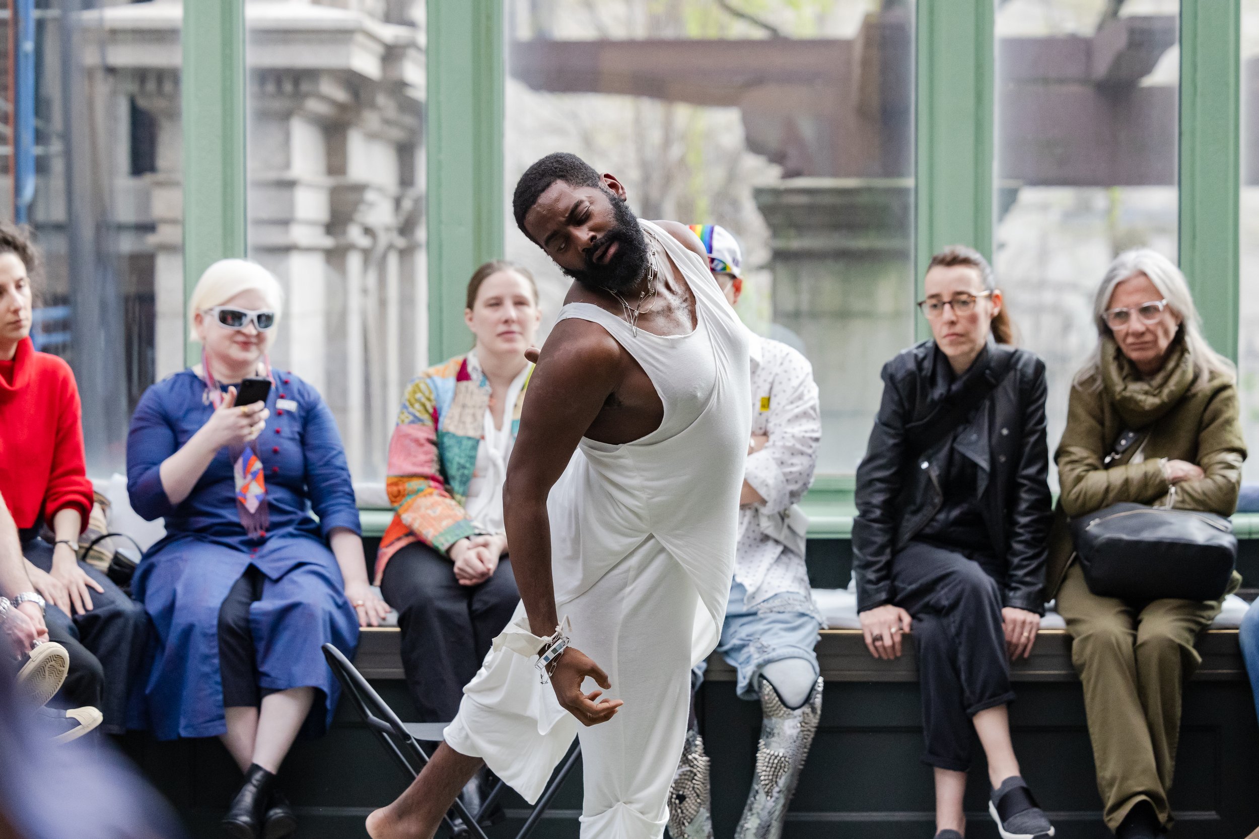 Color photo of Jerron in white twirling in between an audience in a rotunda