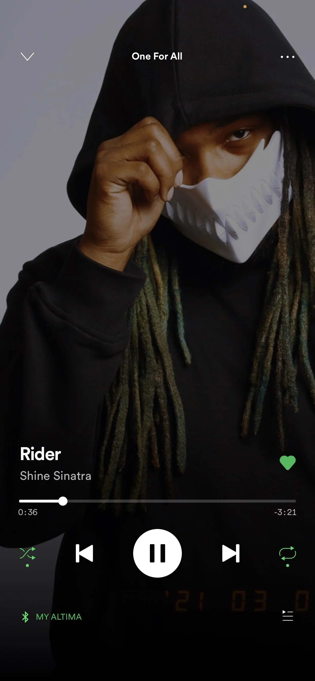 Person wearing a hoodie and mask with long dreadlocks, Spotify interface showing "Rider" by Shine Sinatra.