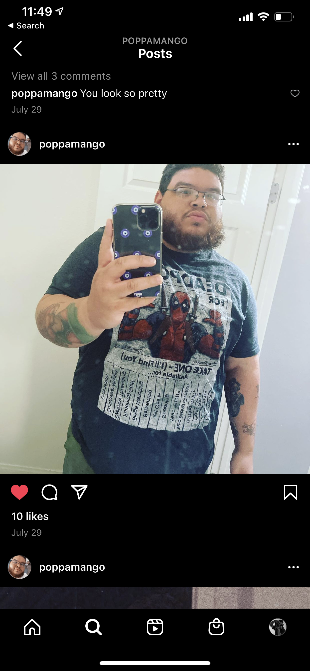 Person taking a mirror selfie wearing a Deadpool t-shirt, holding a phone with an eye-themed case, visible tattoos on their arm.