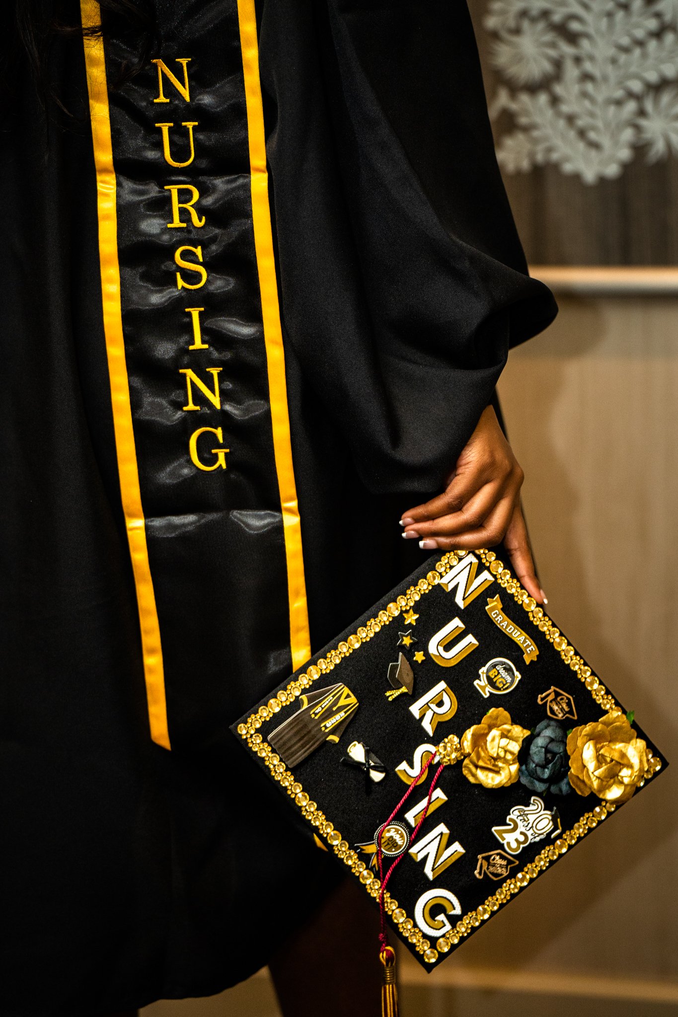Decorated graduation cap and gown with "Nursing" sash and 2023 embellishments.
