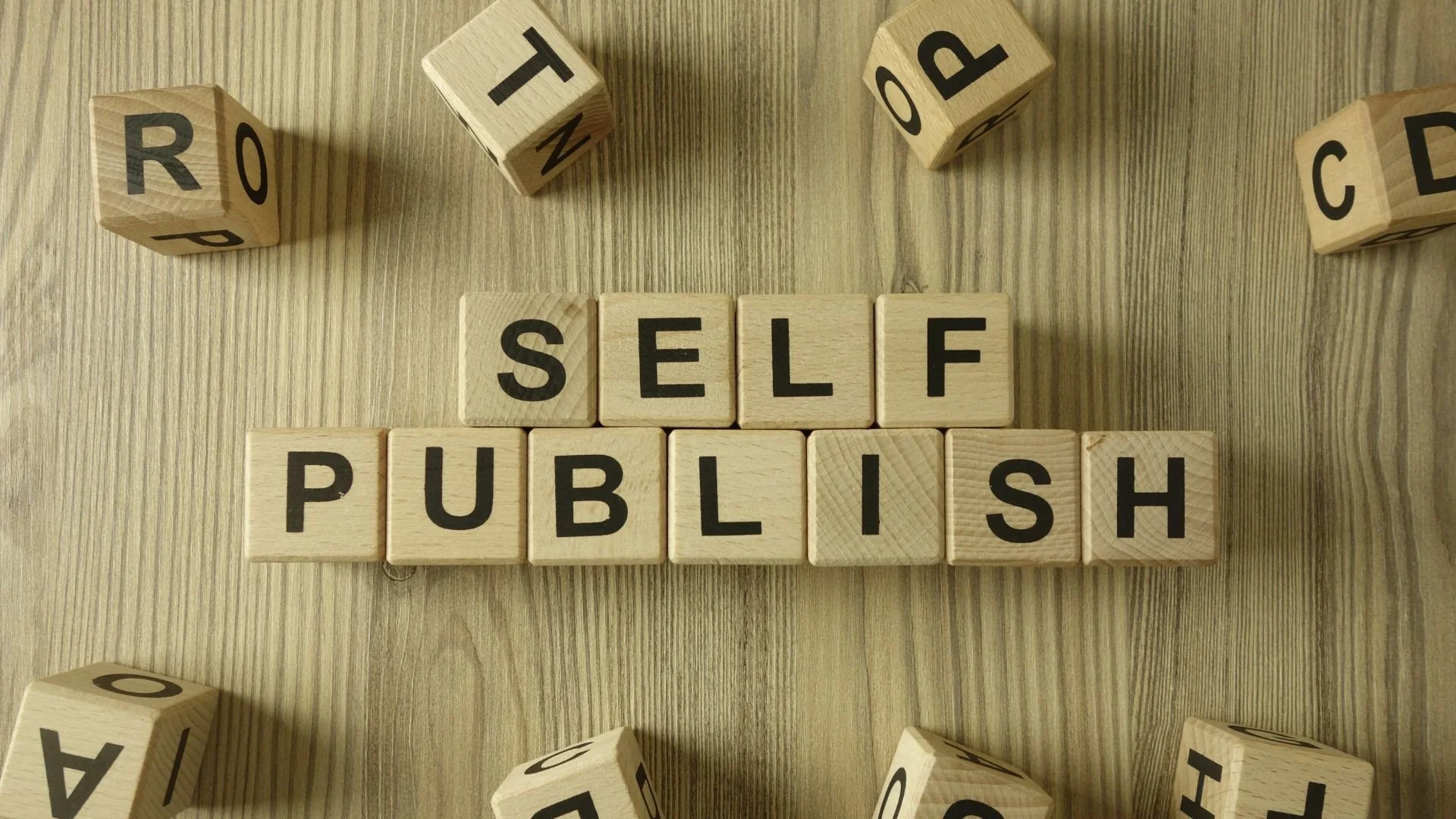 Wooden letter tiles spelling "self publish," representing self-publishing companies in Canada