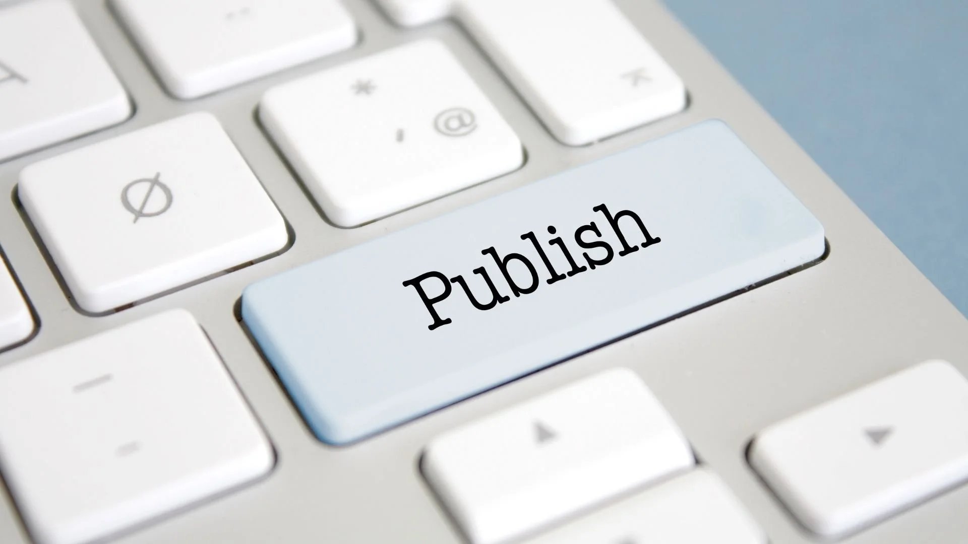 Close-up of a keyboard with a blue "Publish" key, representing publishing a self-published book