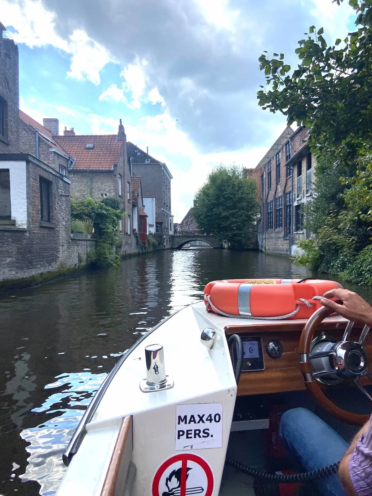 ブルージュの運河クルーズで船上から撮影した景色。橋へ向かって進むボートと中世の街並み