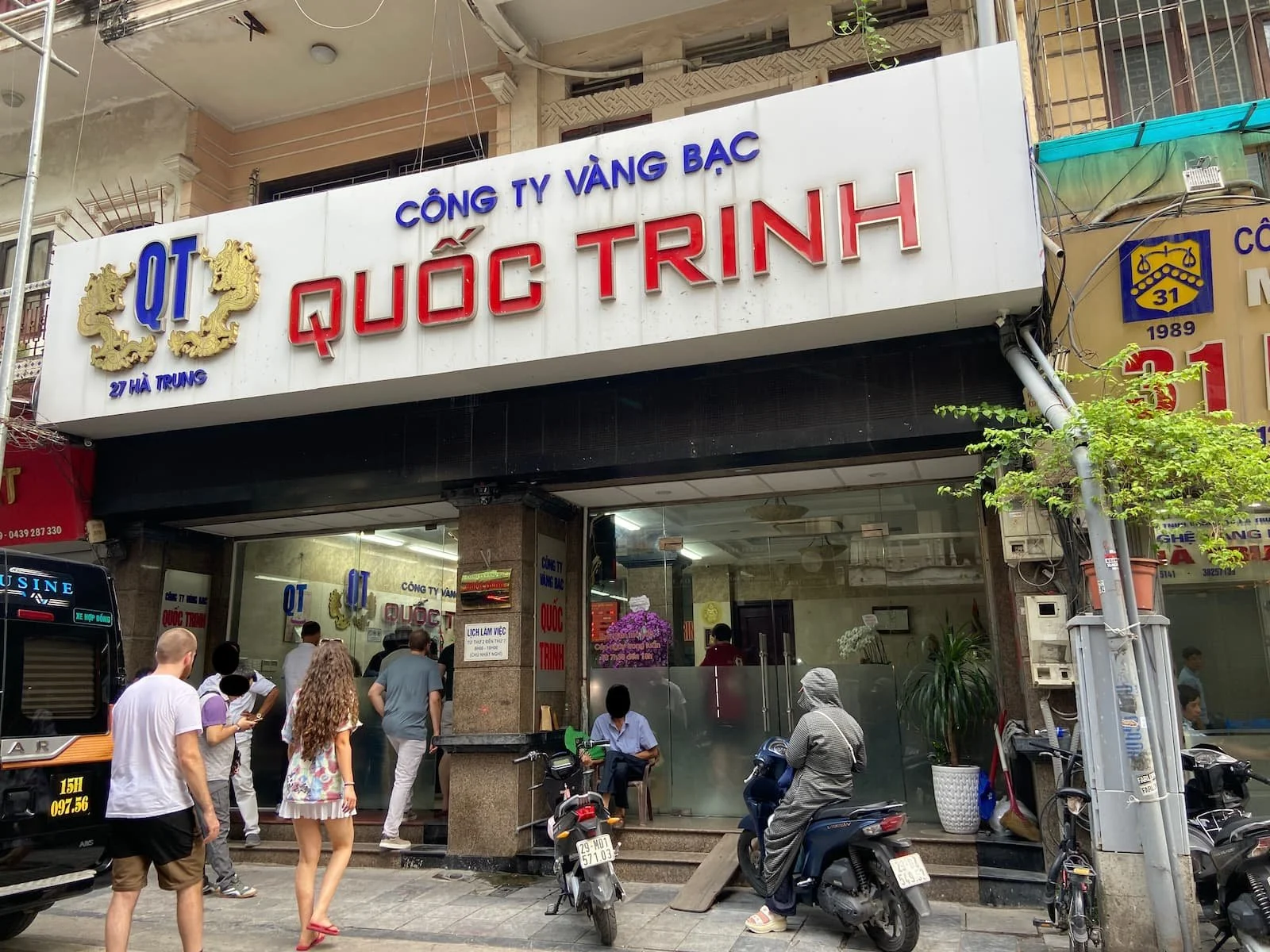 ベトナム・ハノイ旧市街のHà Trung（ハーチュン通り）にある両替所QUỐC TRINH（クオック・チン）の外観。外国人旅行者が店内や入口付近に集まっている。