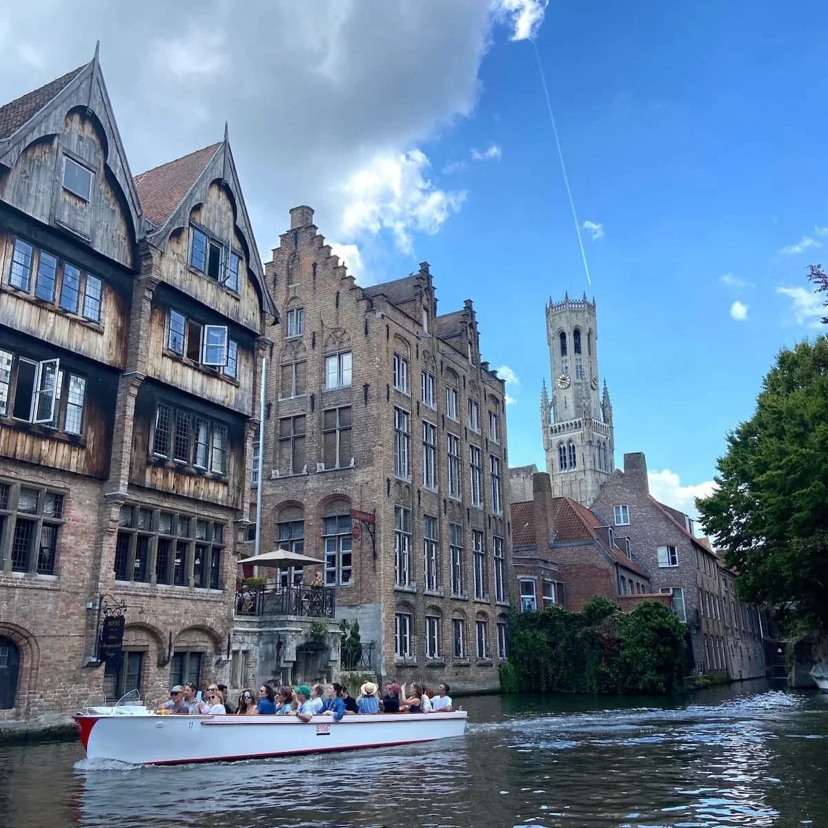 ブルージュの運河を進む観光ボートとレンガ造りの街並み（ベルギー）