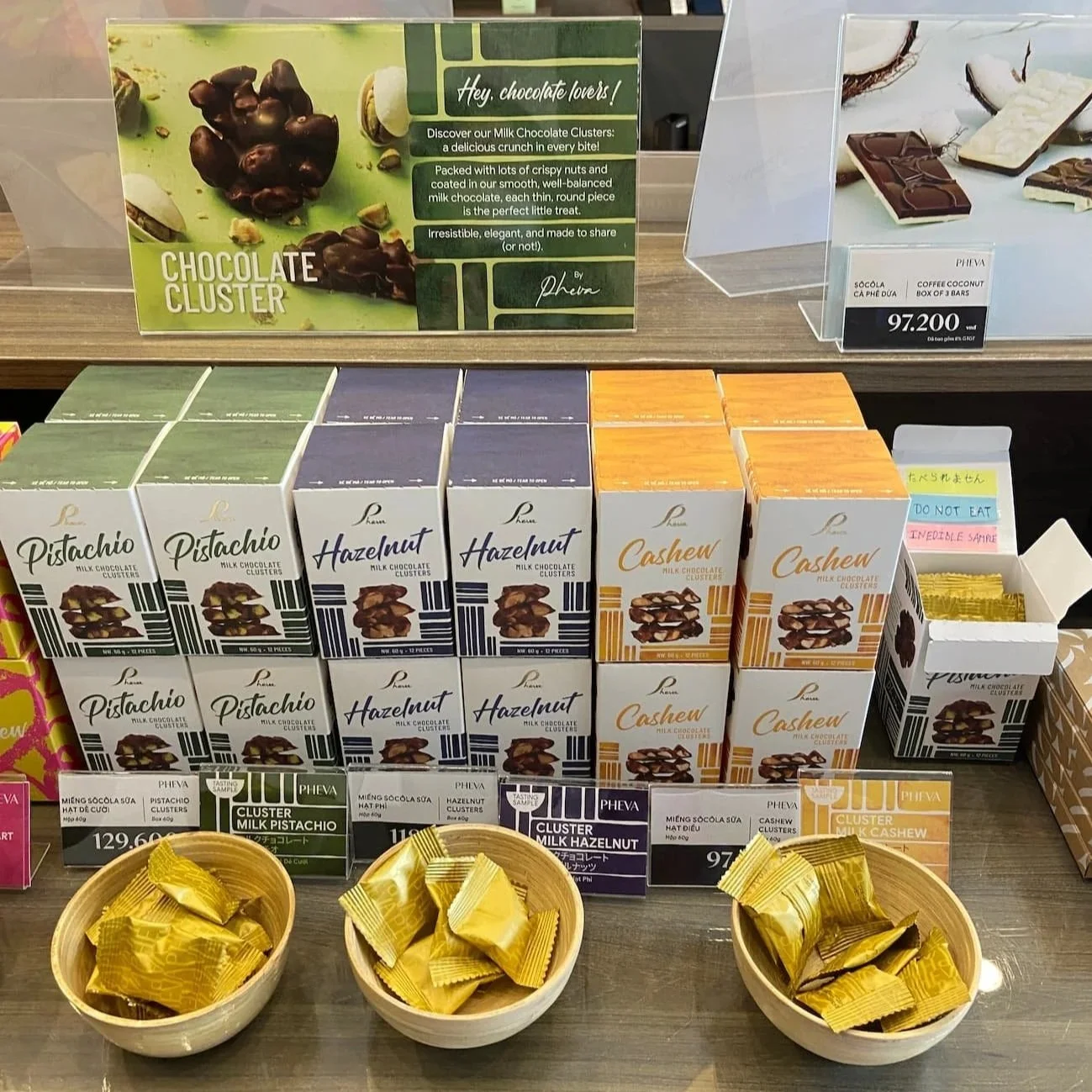 Pheva(フェヴァ)の新作「CHOCOLATE CLUSTERS」。カシューナッツ・ヘーゼルナッツ・ピスタチオの3種類が並ぶハノイ店のディスプレイ(2025年撮影)