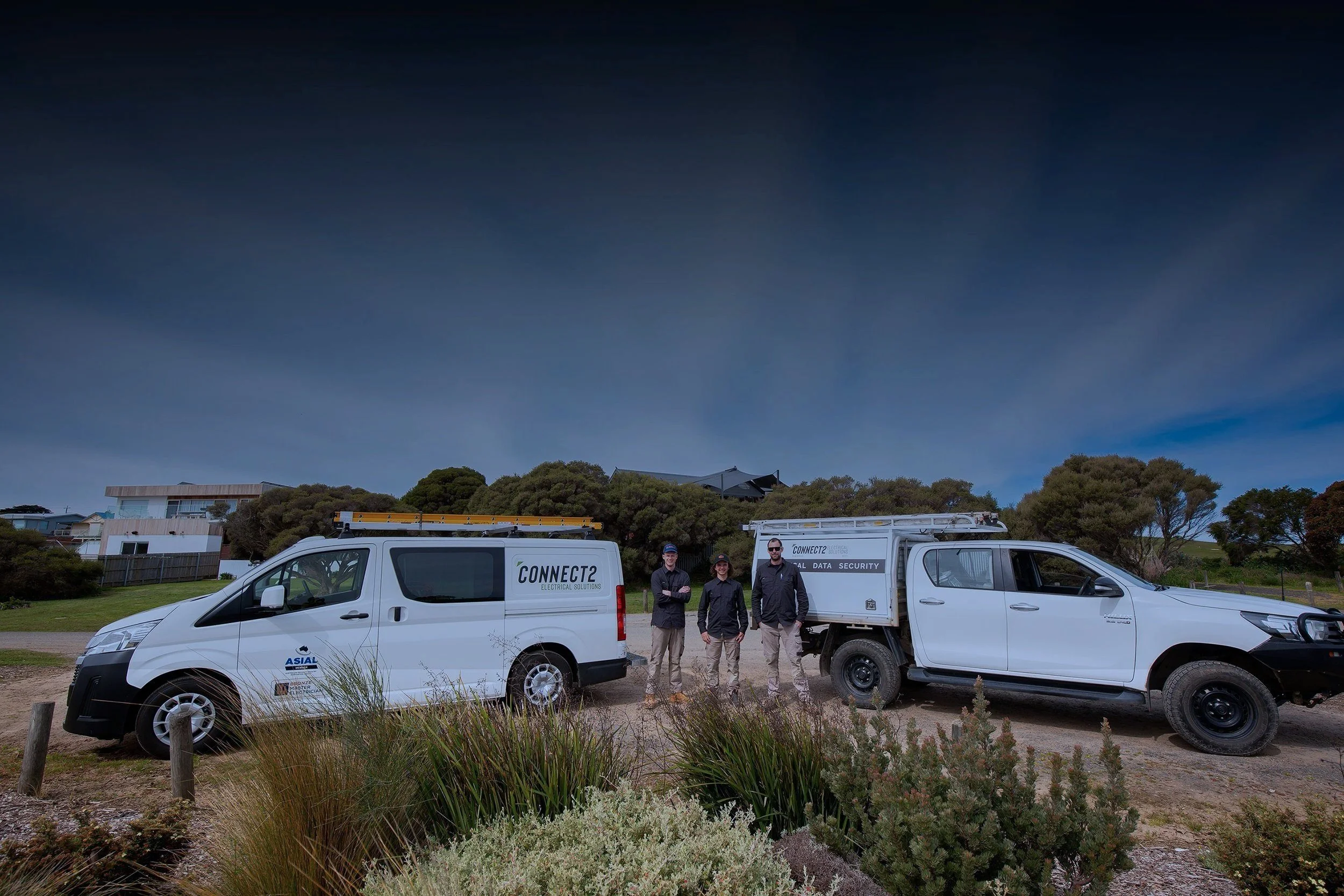 three electricians and two vans in a carpark