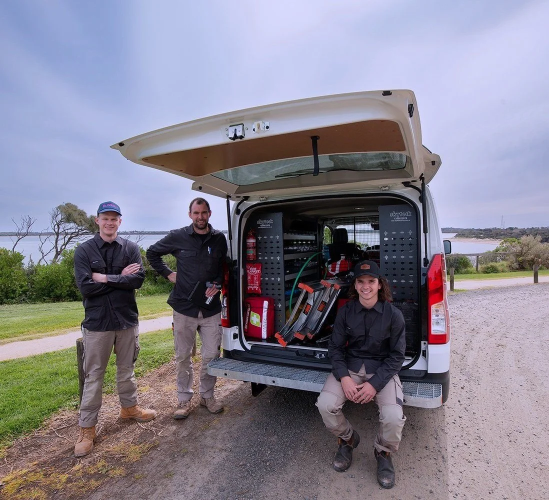 three electricians sitting at the back of a van