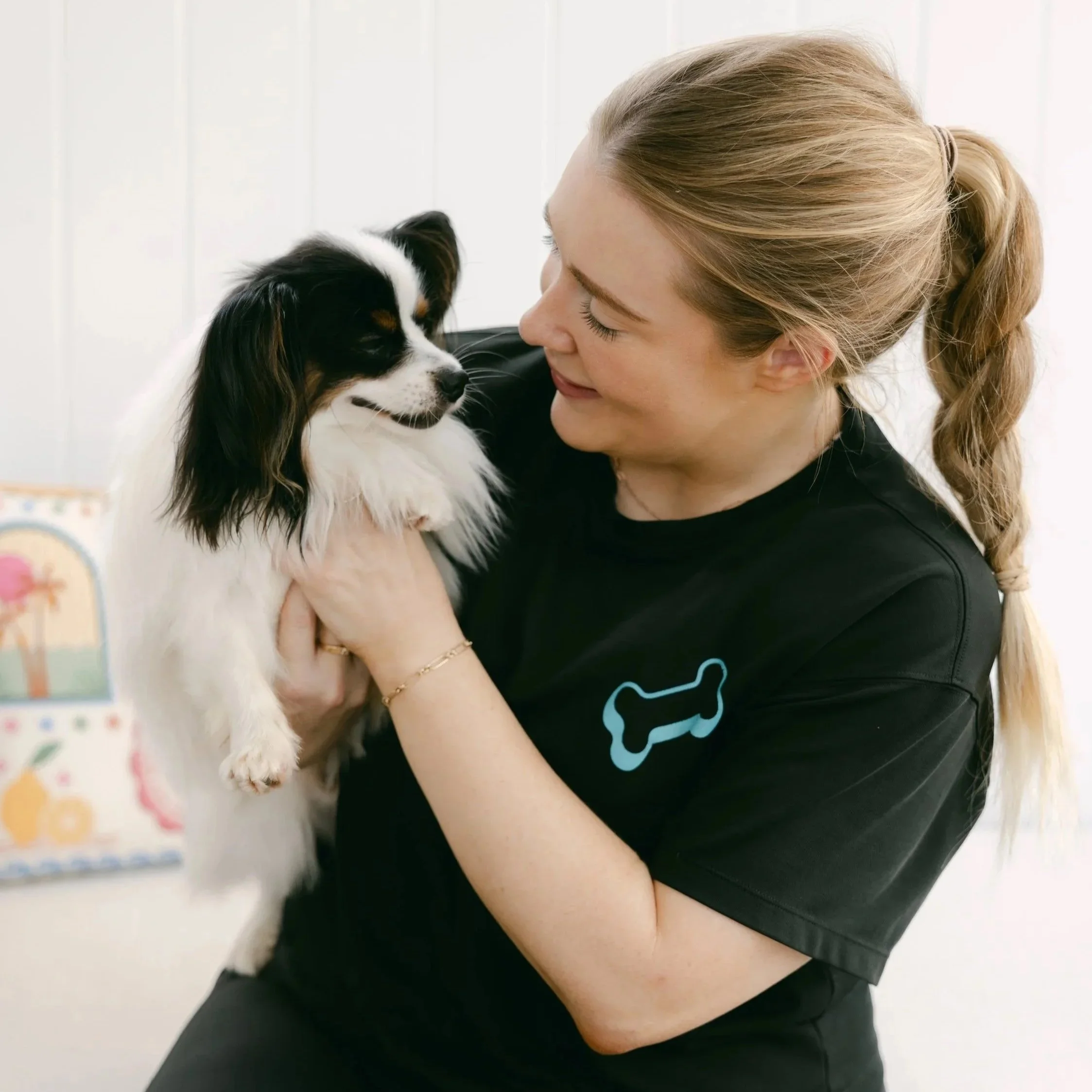 Laura holding a black and white puppy close to her face, both appearing happy and affectionate.