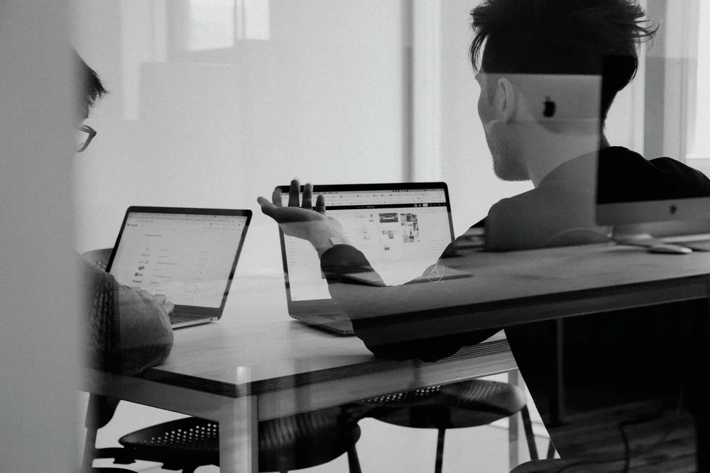 Two people talking through a business plan at laptops