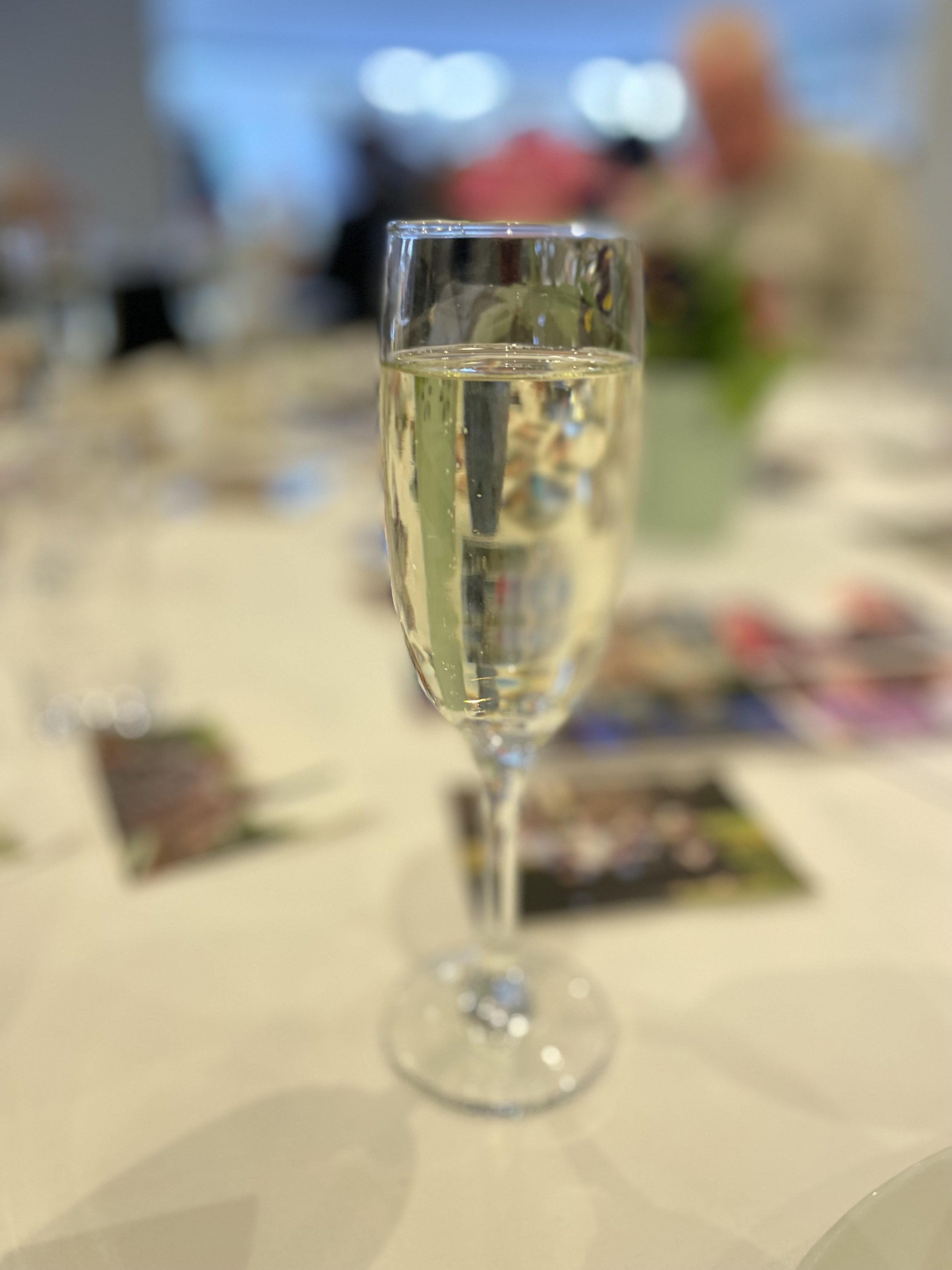 A flute glass filled with prosecco stands on a table covered in photos
