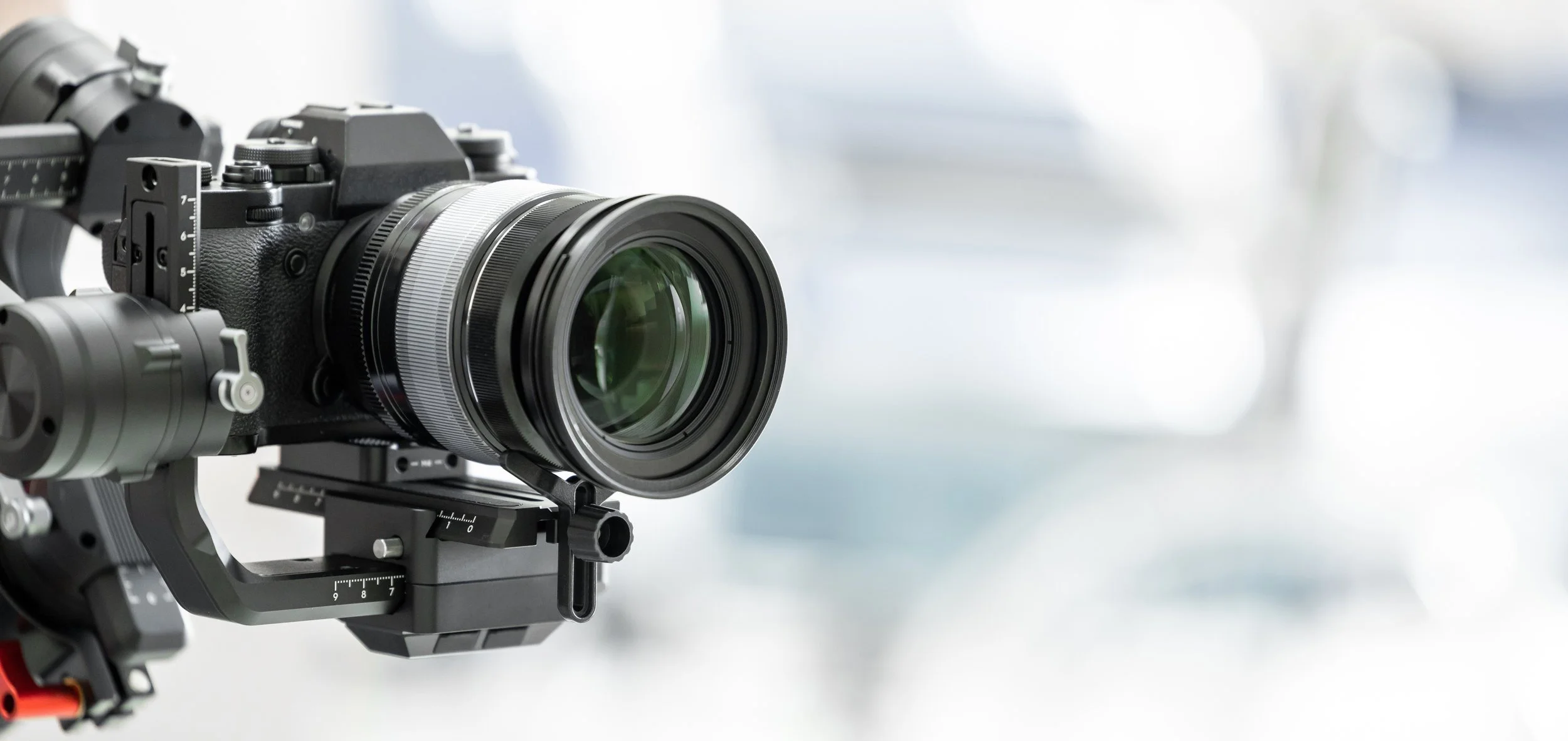 Close-up of a professional camera with a large lens mounted on a gimbal stabilizer, used for smooth video recording.