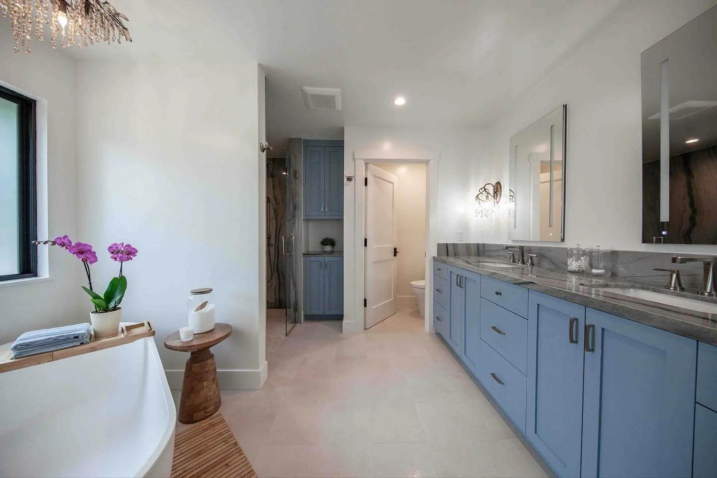 Serene and simply beautiful.
This primary bathroom design by Khara and Amber features a soaking tub, large custom blue vanity, gorgeous natural stone, and an ample walk-in shower. The ultimate spa experience. 
Builder: @trumbleconstruction