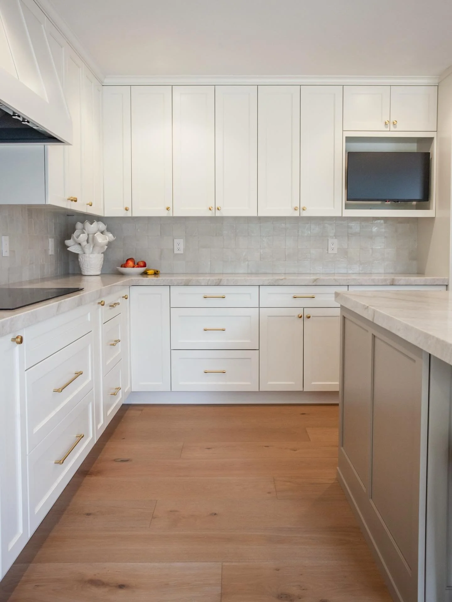 Quiet luxury exudes from this kitchen. Featuring a soft color palette, handmade zellige tile backsplash, quartzite countertops, paneled appliances and brass fittings.