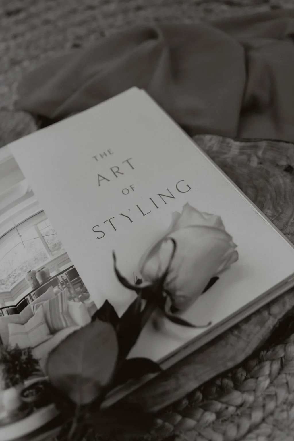 Art book titled 'The Art of Styling' beside a fresh rose, symbolizing sophisticated brand photography and stylish visual composition.